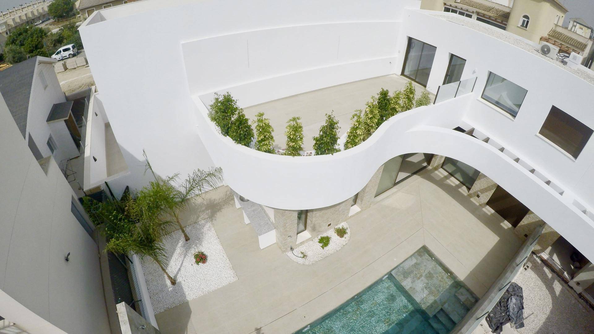 Weitläufige Luftaufnahme der modernen Villa mit geschwungener Architektur und begrünter Dachterrasse.