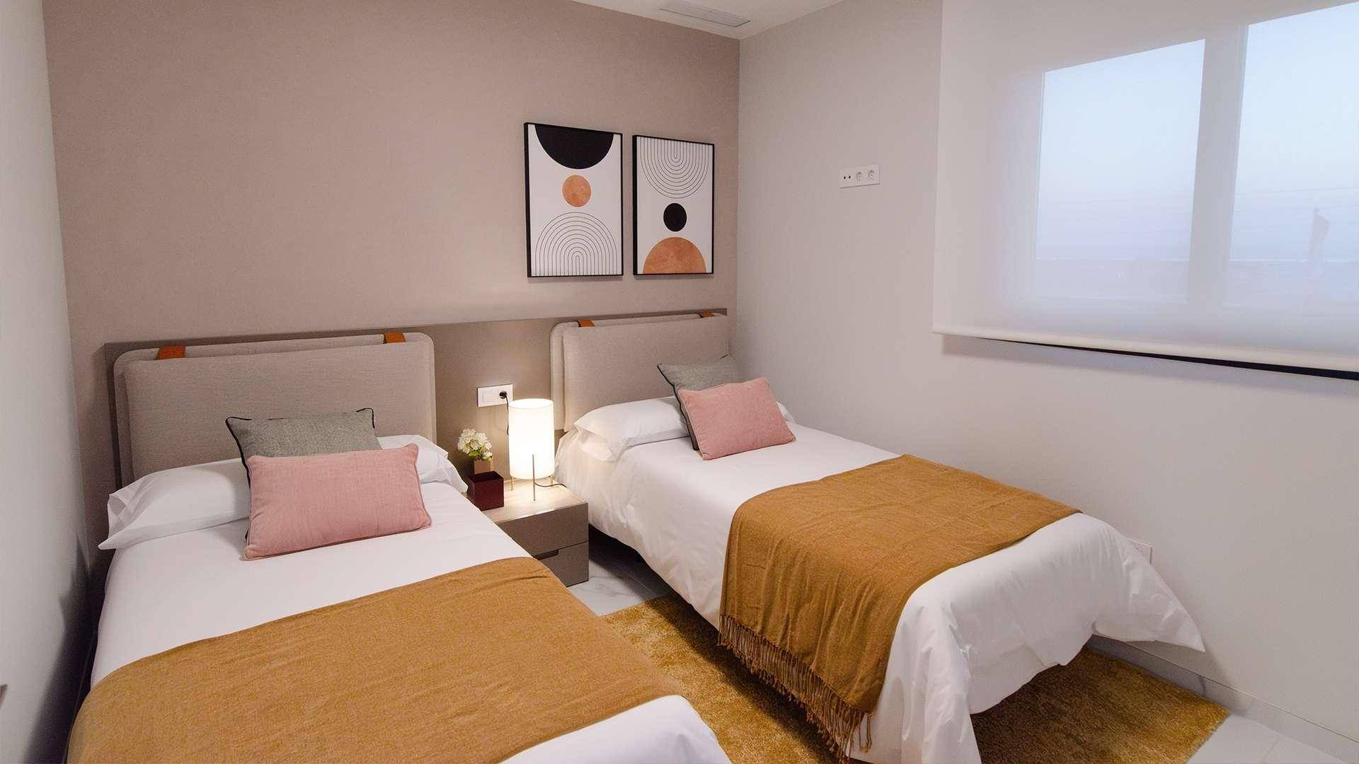 Helles Schlafzimmer mit zwei Einzelbetten, modernen Bildern und neutralen Farbtönen.