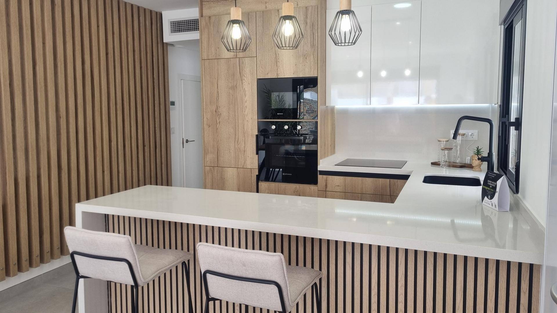Moderne Küche mit Holzfronten, weißen Arbeitsplatten und integrierten Geräten.