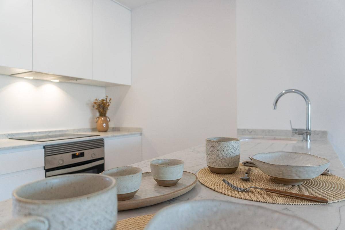 Moderne Küche mit weißer Arbeitsplatte, Induktionskochfeld und integriertem Backofen.