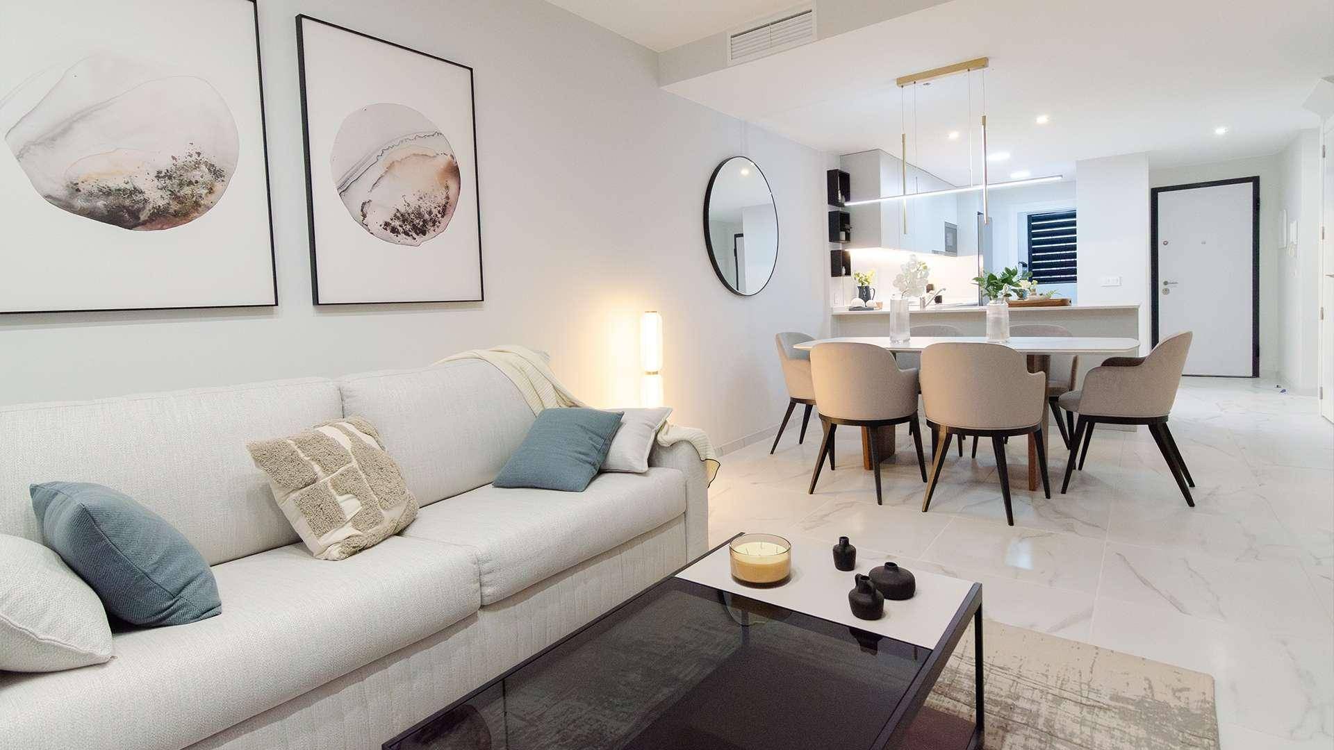 Offener Wohn-Essbereich mit modernem Sofa, Esstisch und integrierter Küche in hellem Design.
