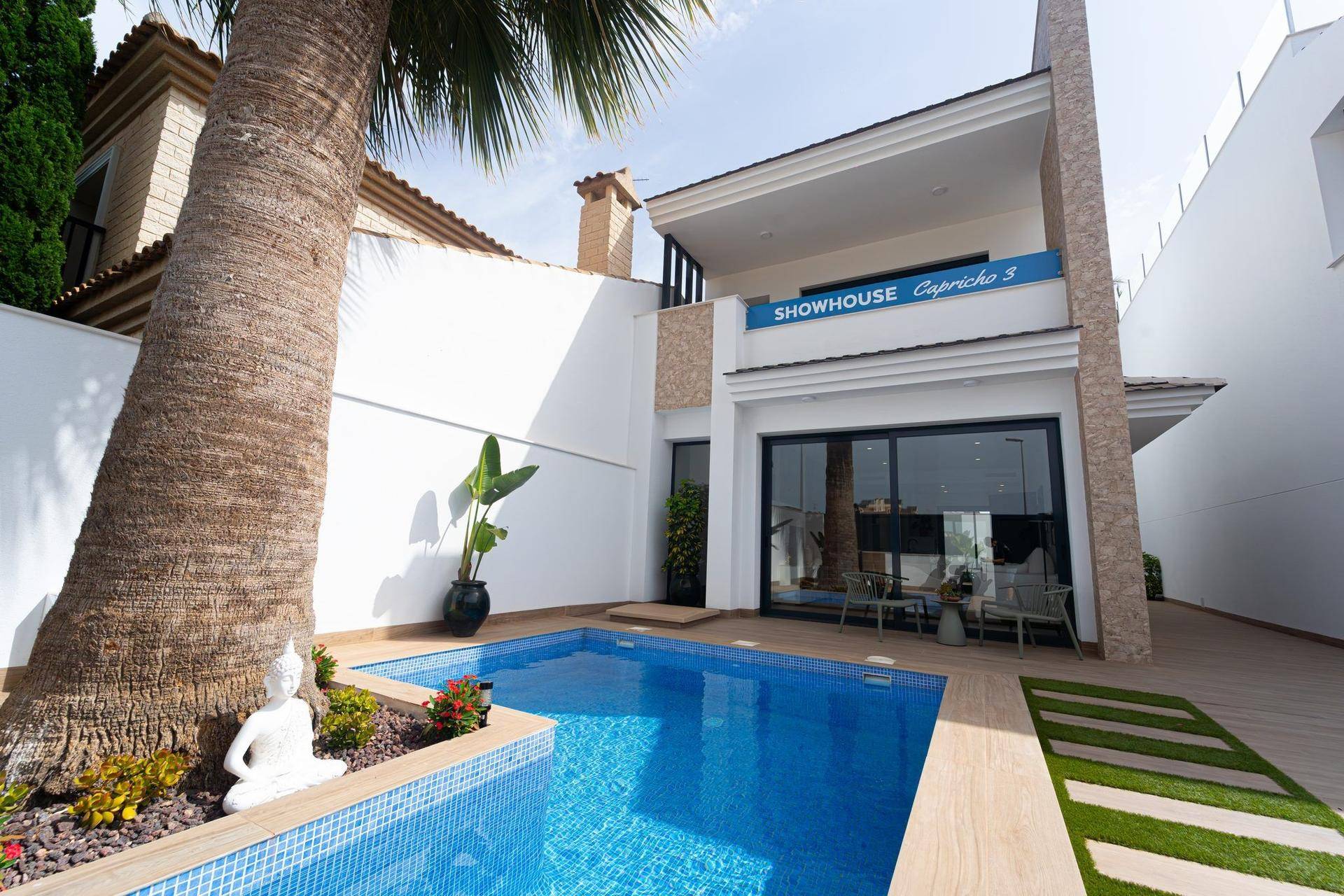 Außenbereich mit kleinem Pool, Palmen und der modernen Fassade des Showhauses.
