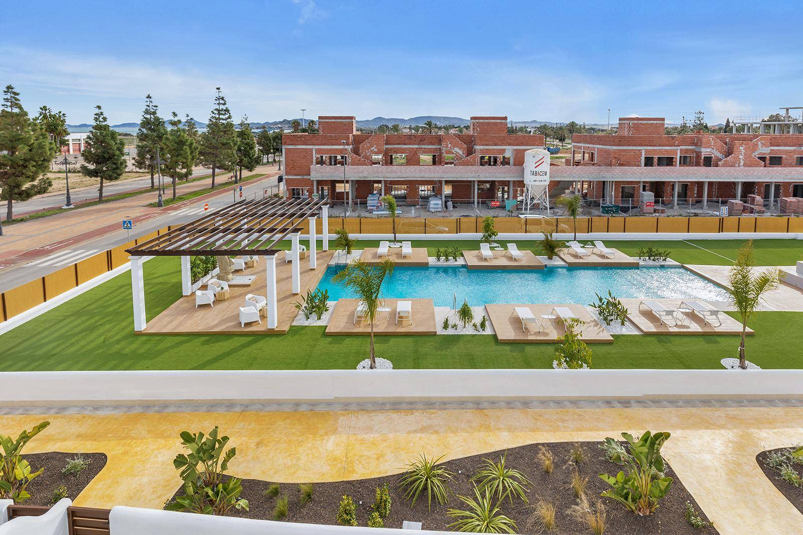 Gemeinschaftlicher Außenbereich mit großem Pool, Liegeflächen und mediterraner Bepflanzung.
