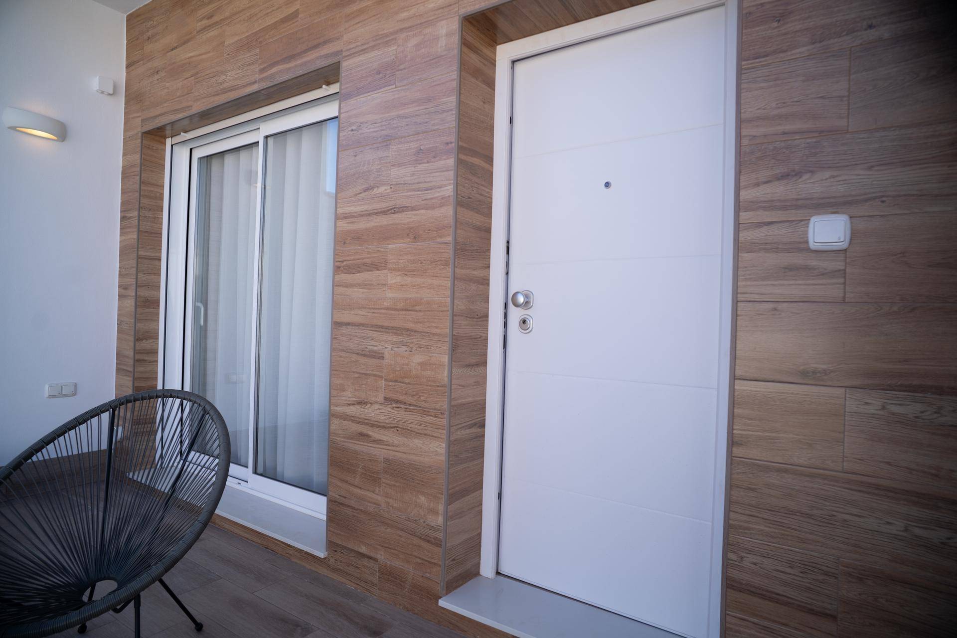 Moderne Eingangstür und Glasschiebetür mit Holzverkleidung an der Fassade.