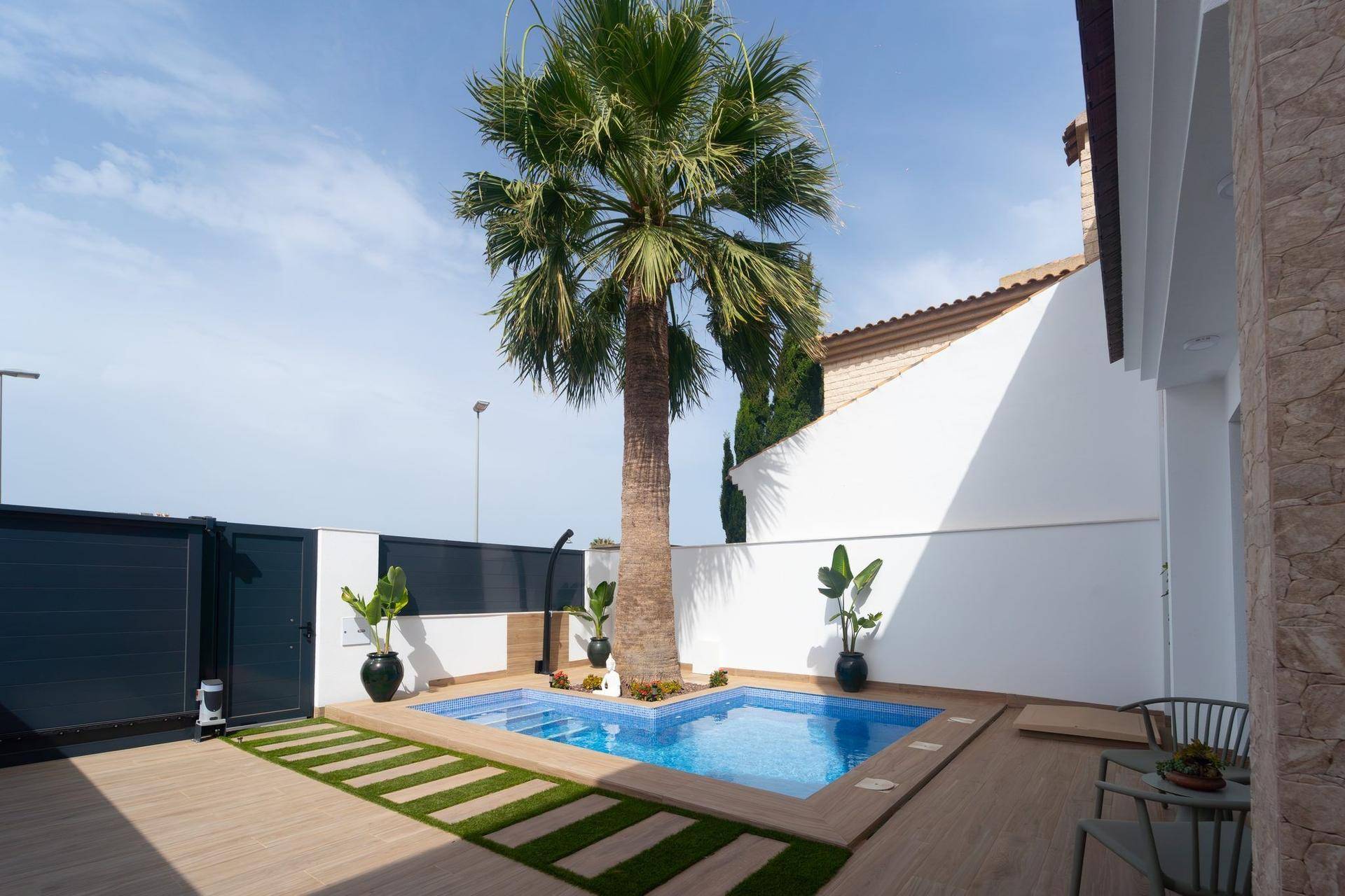 Sonniger Gartenbereich mit kleinem Pool, Palme und Sitzgelegenheiten für entspannte Stunden.