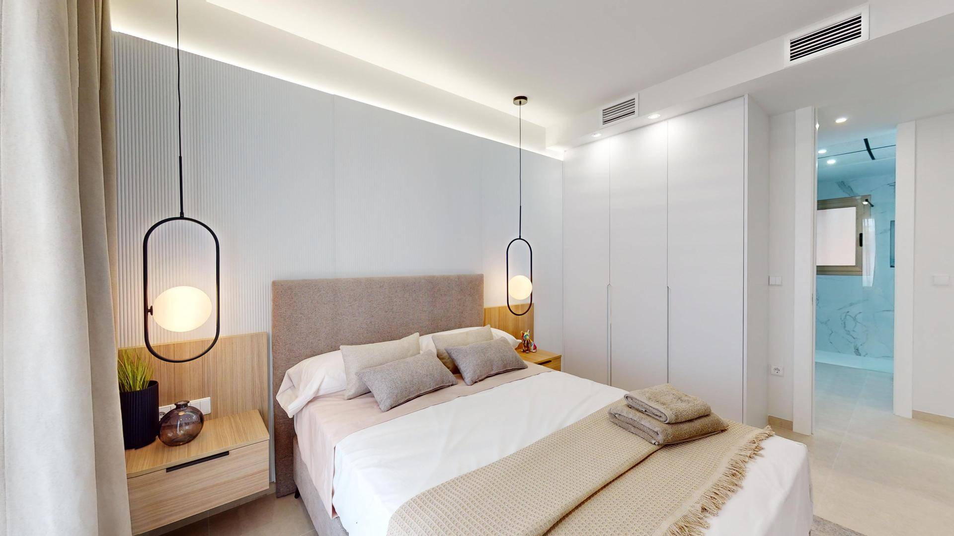Helles Schlafzimmer mit Doppelbett, integrierten Kleiderschränken und modernen Hängelampen.