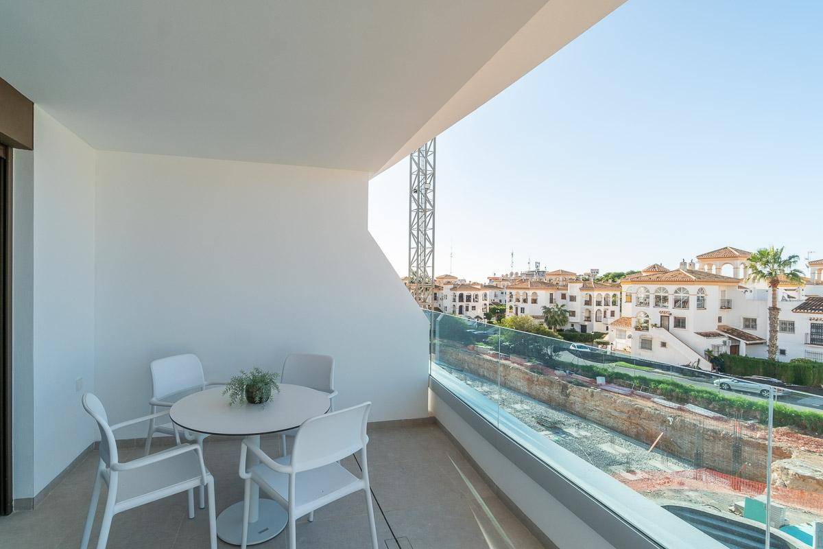 Heller Balkon mit modernen Gartenmöbeln, Glasgeländer und Blick auf die Umgebung.