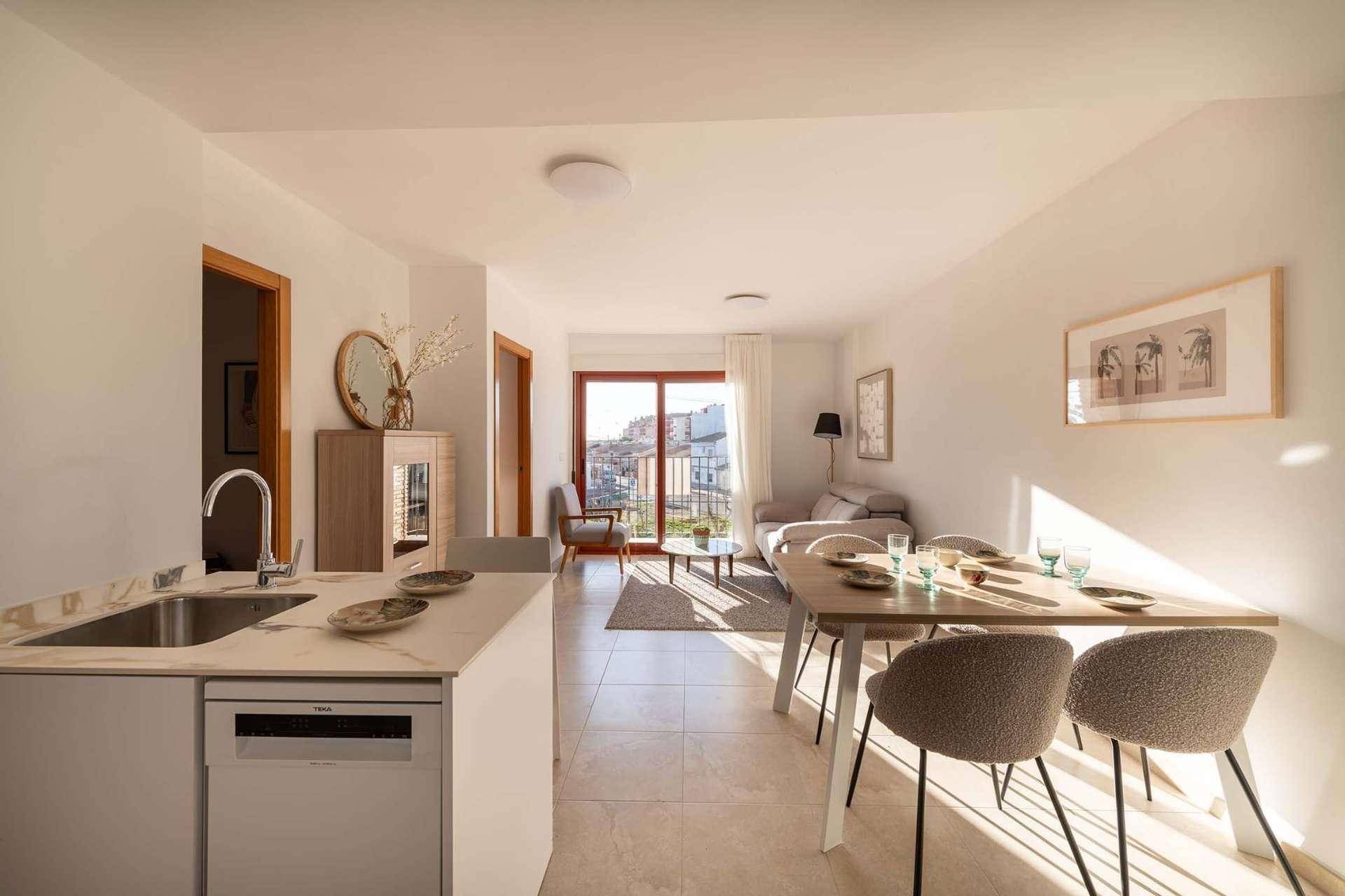 Moderner offener Wohn-Essbereich mit integrierter Küche, Esstisch und Blick auf den Balkon.