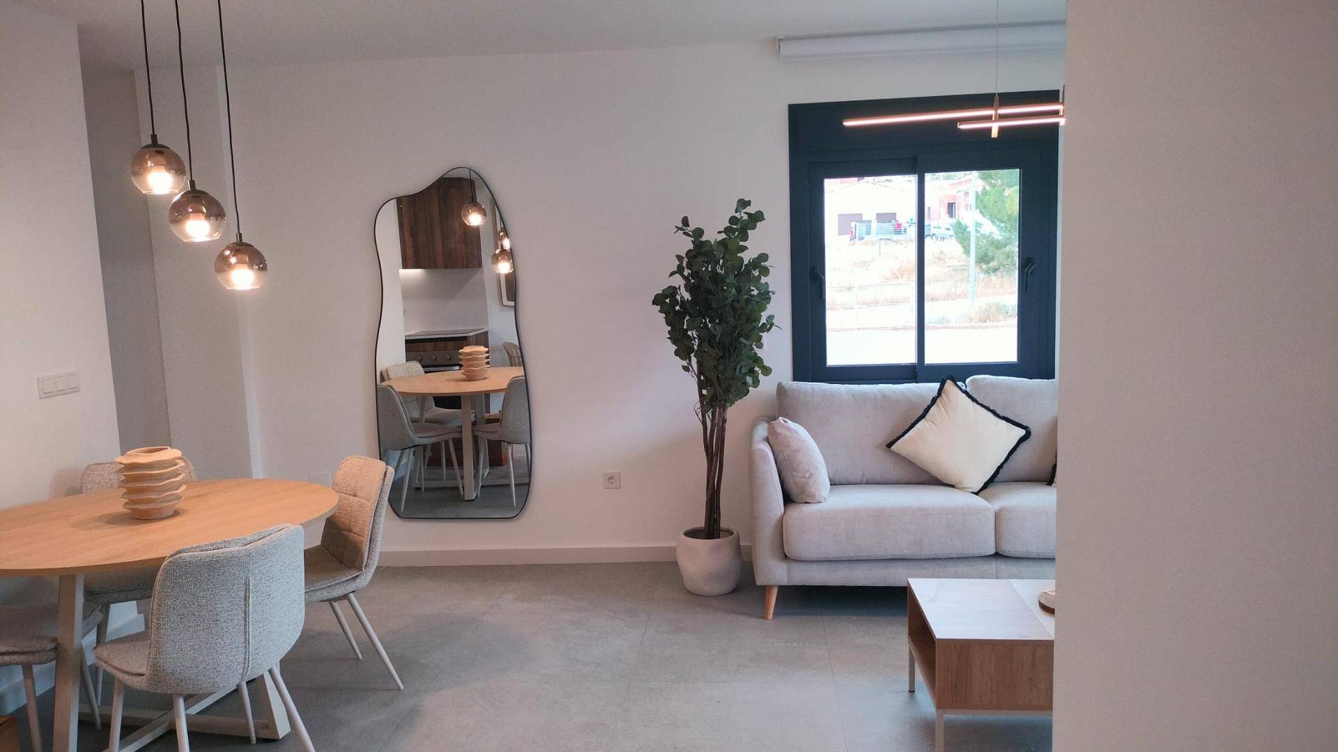 Moderner Wohn-Essbereich mit beigem Sofa, Holztisch und großen Fenstern.