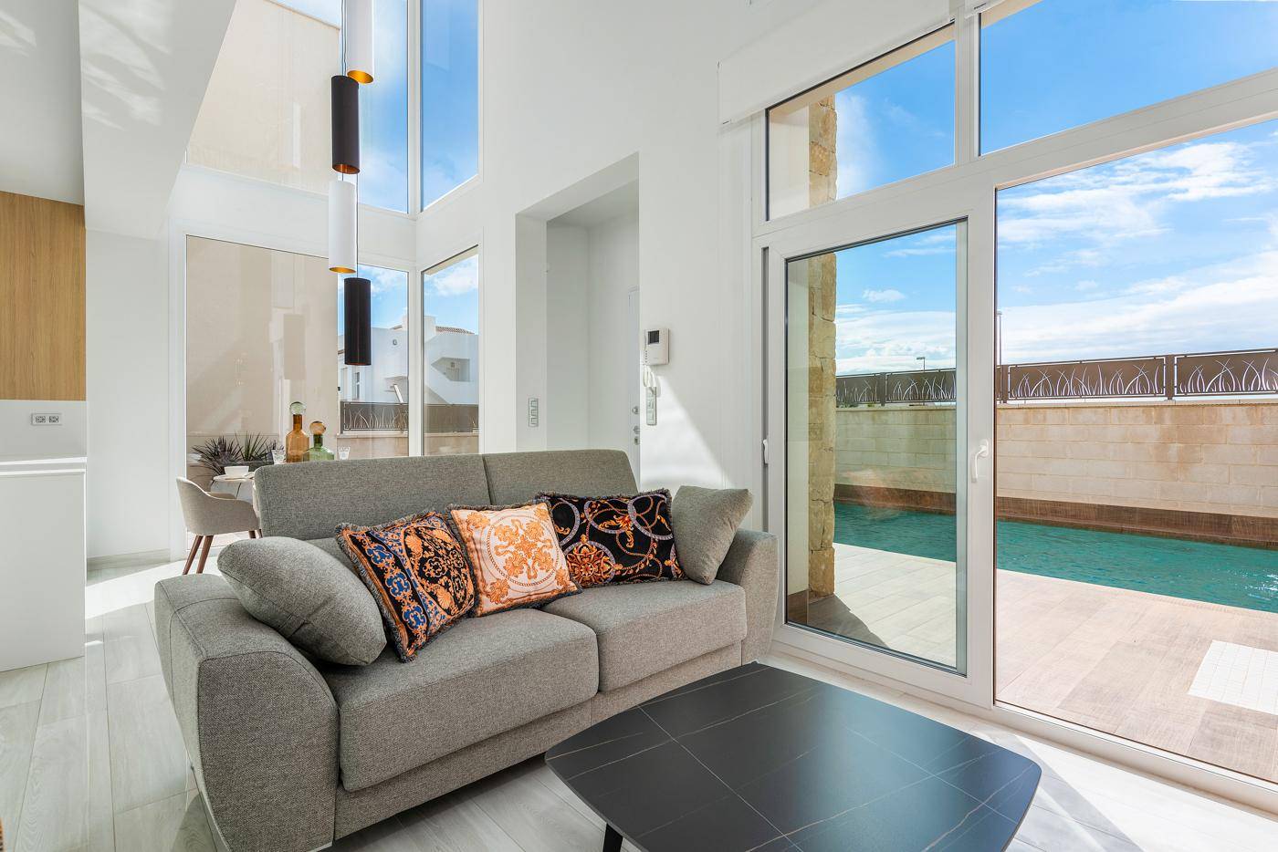 Helles Wohnzimmer mit großen Fenstern, die den Blick auf den privaten Pool freigeben.