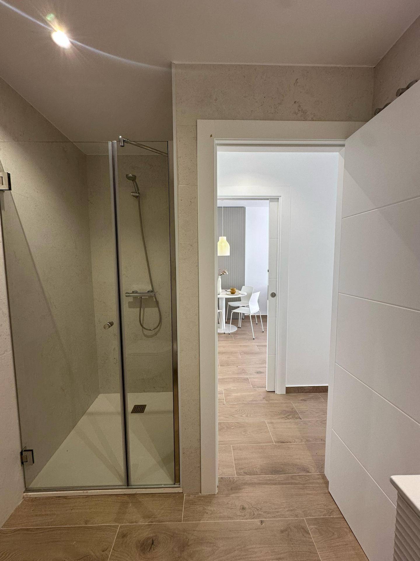Modernes Badezimmer mit begehbarer Dusche und Fliesenboden in Holzoptik.