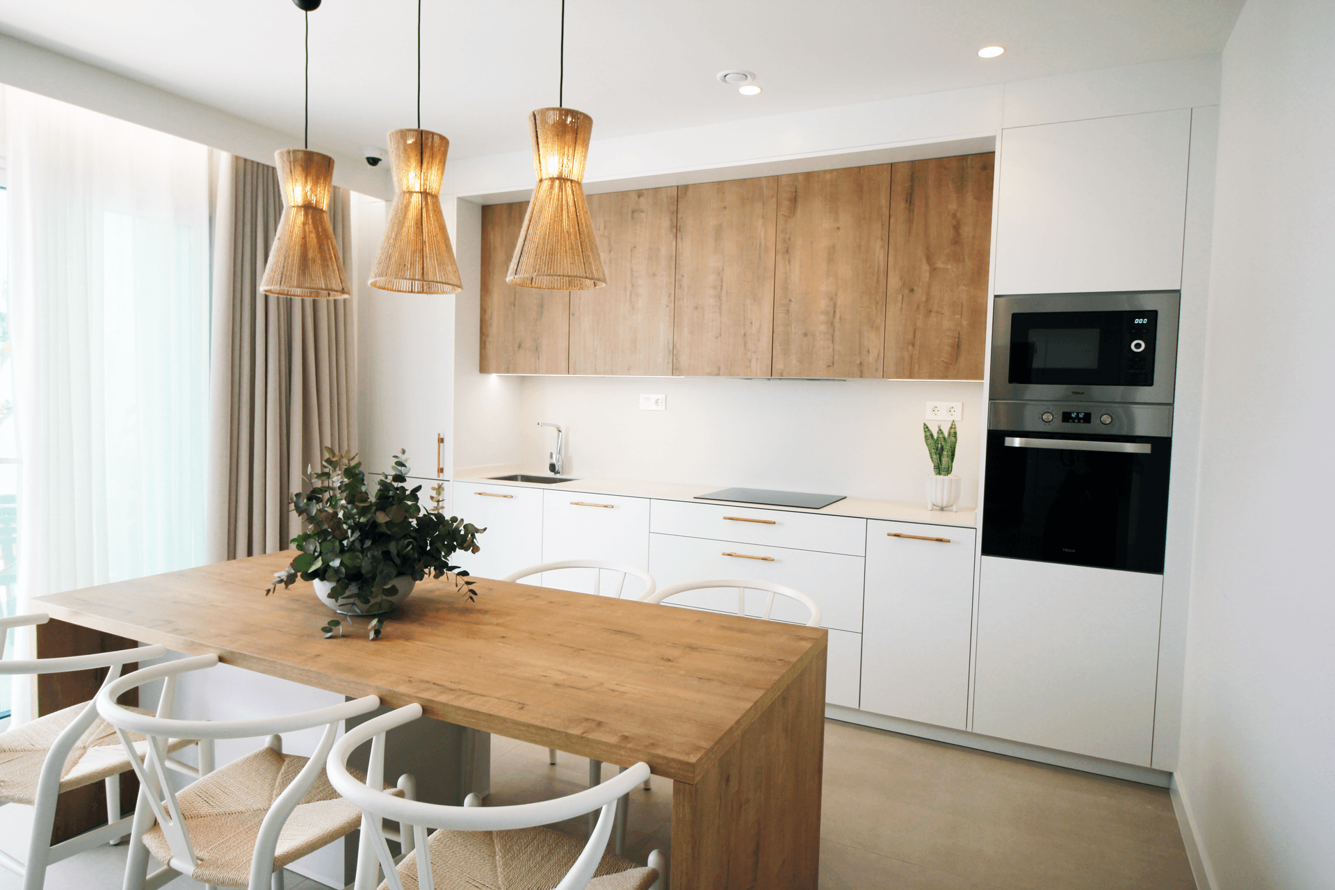 Helle, moderne Küche mit Essbereich an der Kücheninsel, integrierten Geräten und Holzakzenten.