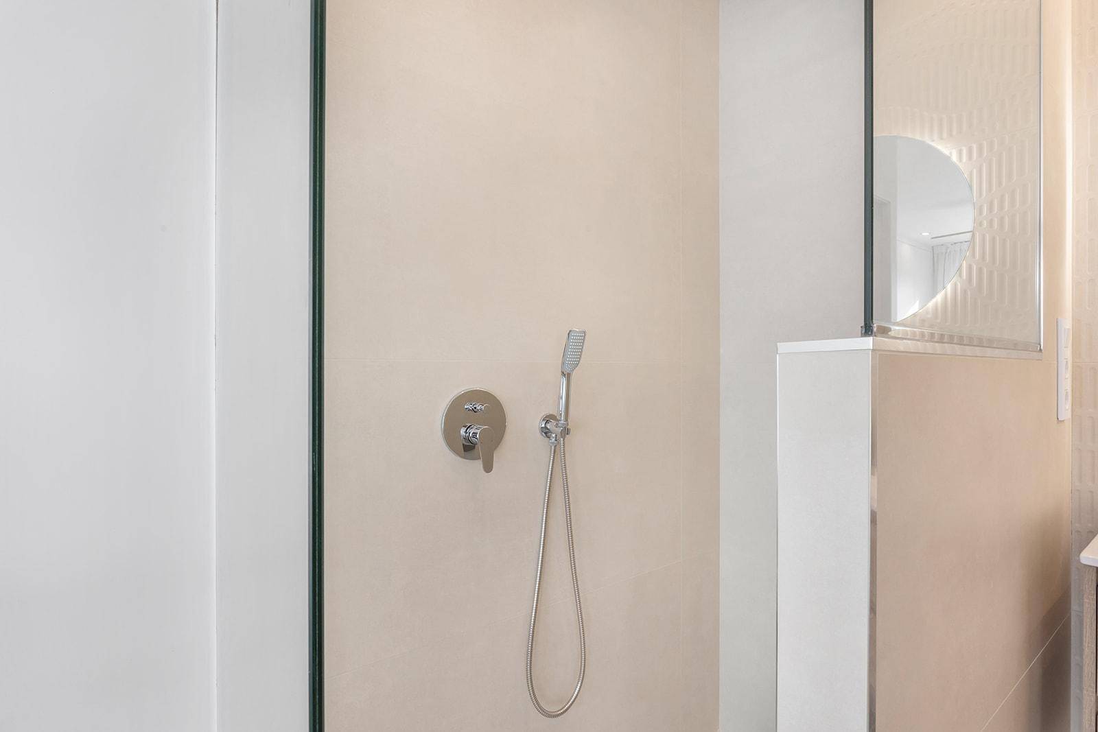 Detailaufnahme einer modernen begehbaren Dusche mit Regenduschkopf und Handbrause.