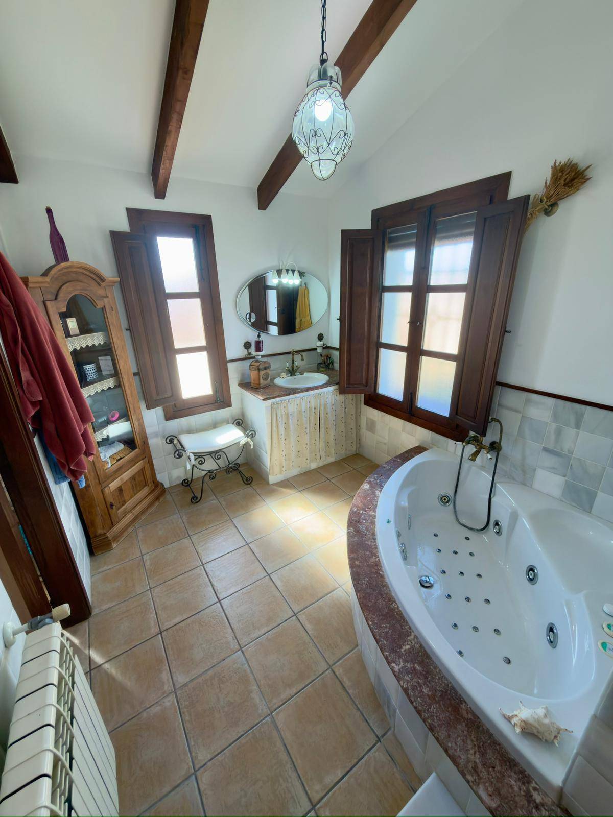 Helles Badezimmer mit Whirlpool, Einzelwaschbecken und zwei Fenstern.