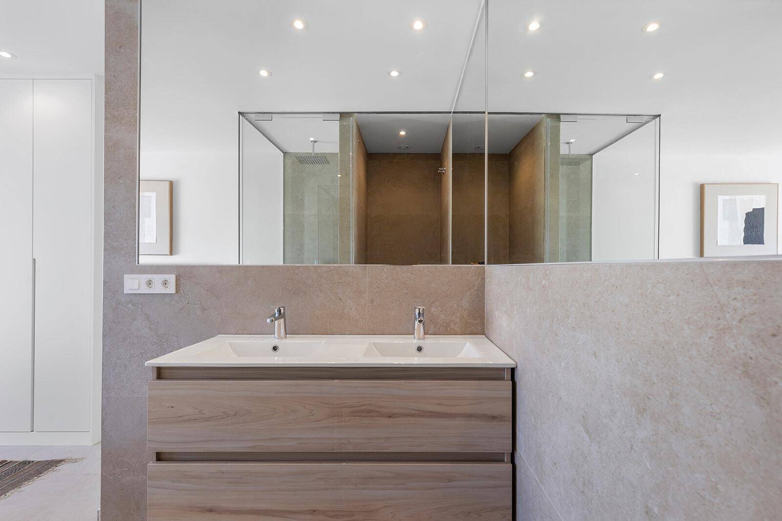 Modernes Badezimmer mit Doppelwaschbecken, großem Spiegel und eleganten Fliesen in Naturtönen.