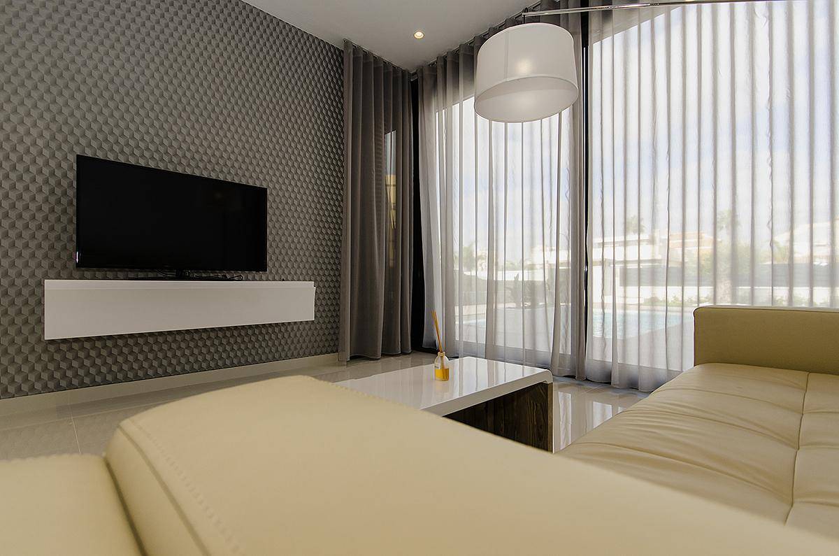 Gemütliches Wohnzimmer mit beiger Couch, Stehlampe und Blick auf den Poolbereich.