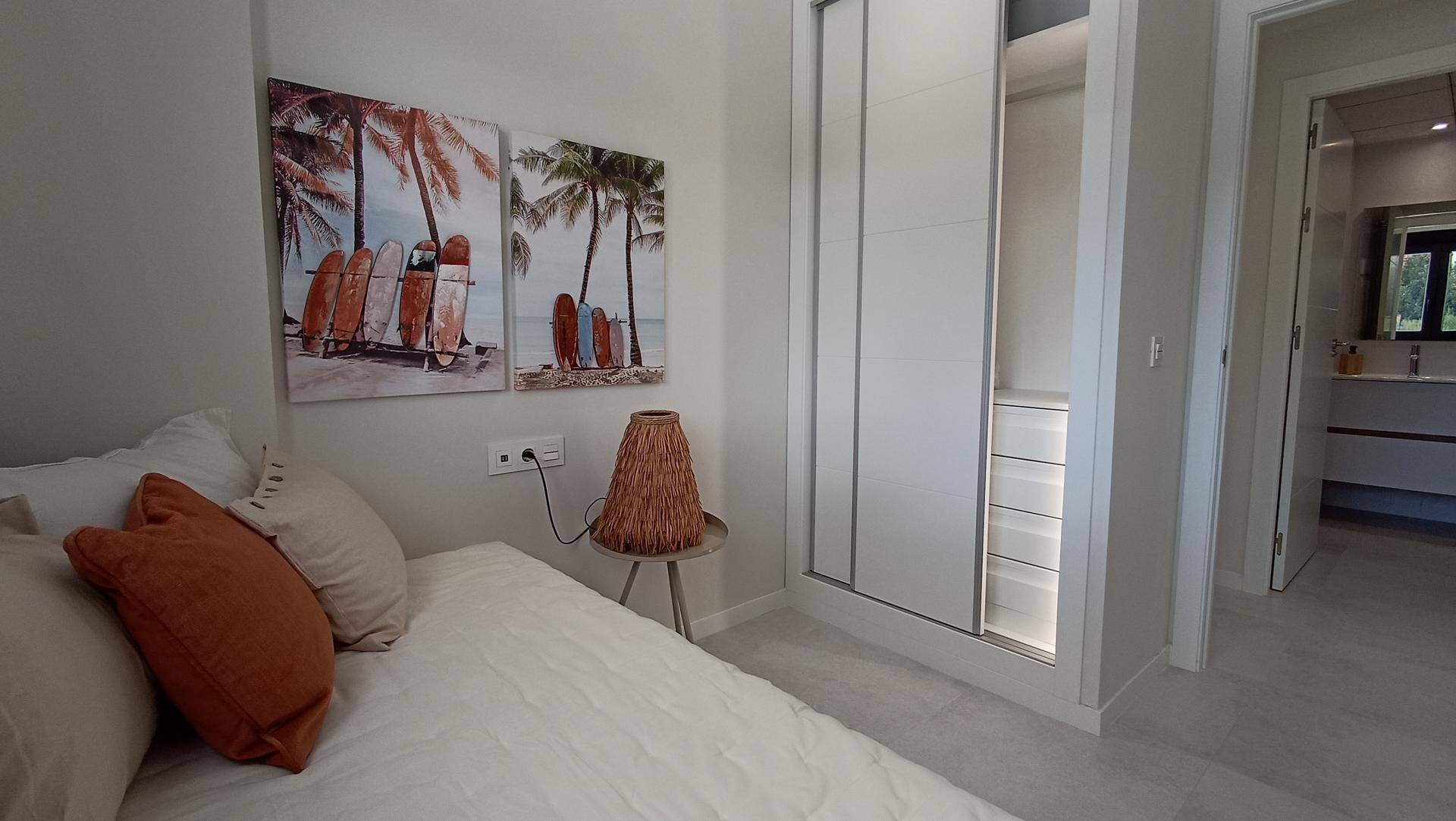 Helles Schlafzimmer mit Einzelbett, Schiebetürenschrank und Zugang zum Badezimmer.