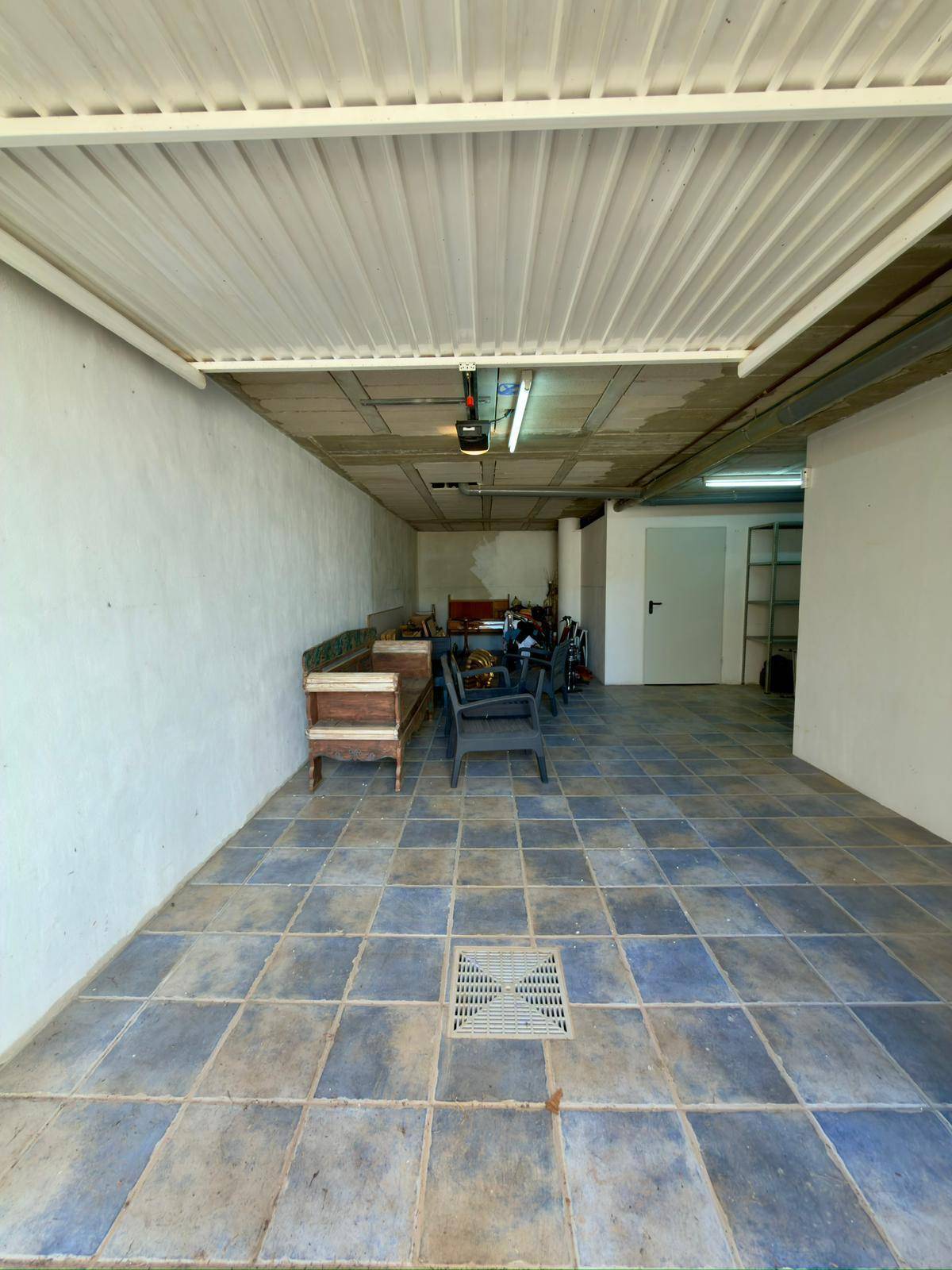 Garage mit Fliesenboden und ausreichend Platz für Fahrzeuge und Lagerung.