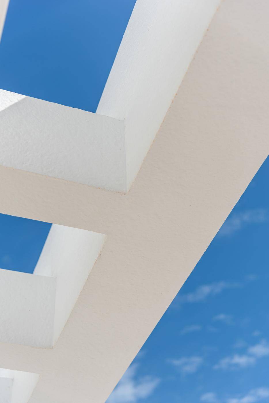 Detailaufnahme einer modernen Pergola-Struktur vor blauem Himmel.