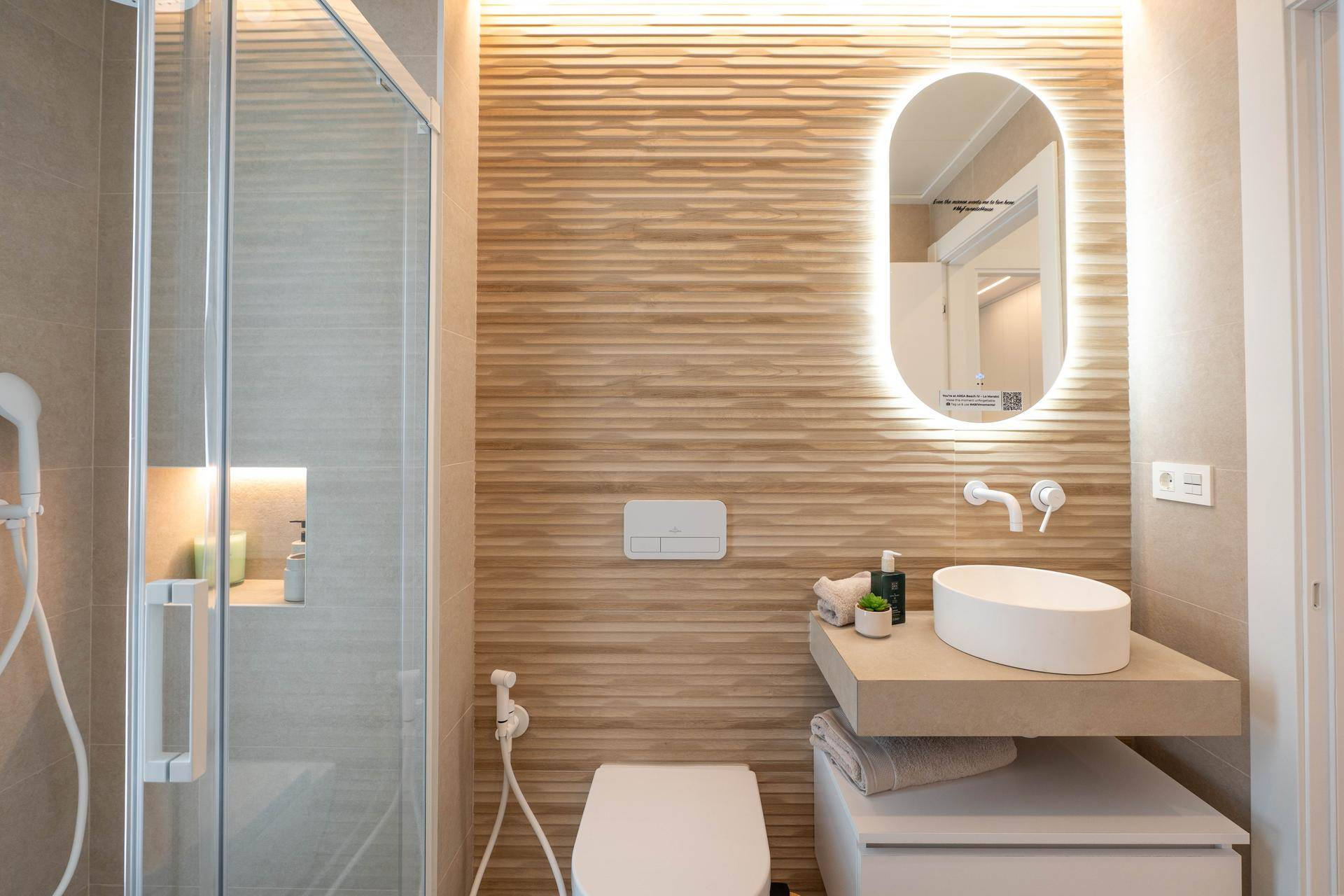 Modernes Badezimmer mit begehbarer Dusche, stilvollen Fliesen und beleuchtetem Spiegel.
