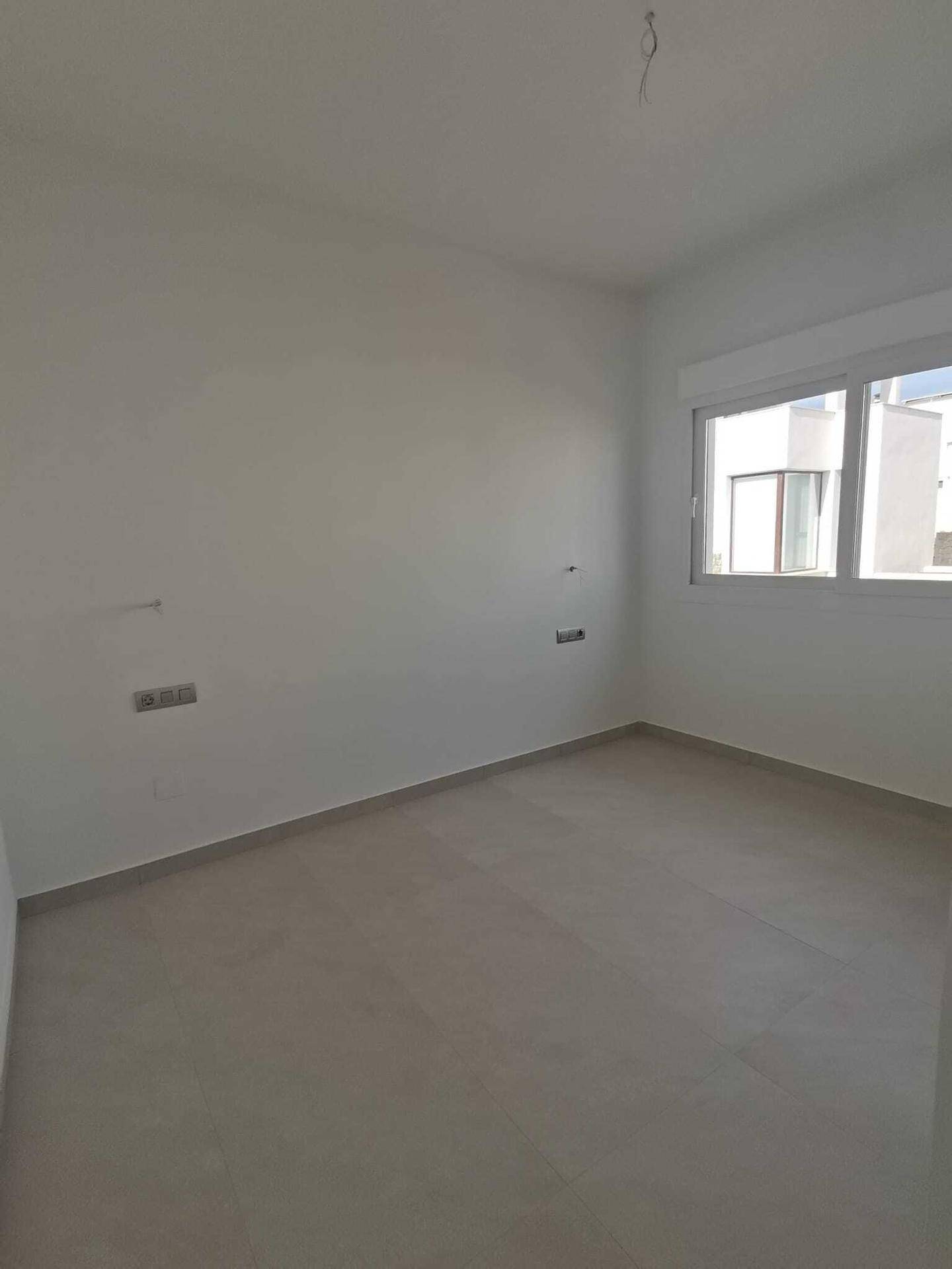 Leeres Schlafzimmer mit hellen Wänden und Fliesenboden, ideal für persönliche Gestaltung und Einrichtung.