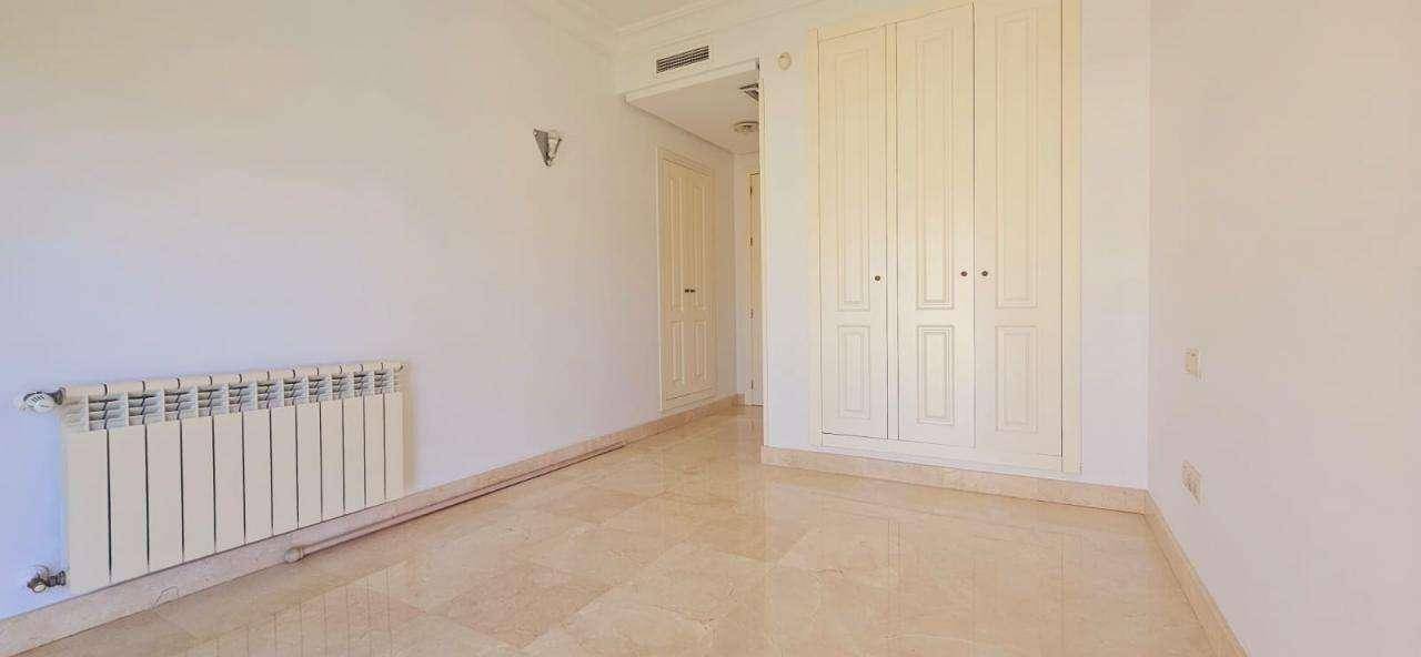Schlafzimmer mit Einbauschrank und glänzendem Marmorboden, bietet viel Stauraum.