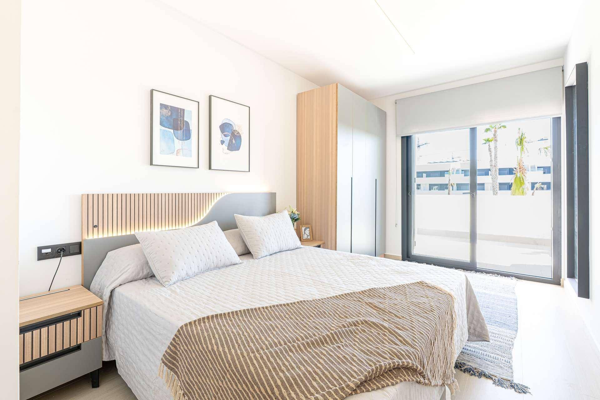 Modernes Schlafzimmer mit großem Fenster, das viel Tageslicht hereinlässt und Zugang nach draußen bietet.