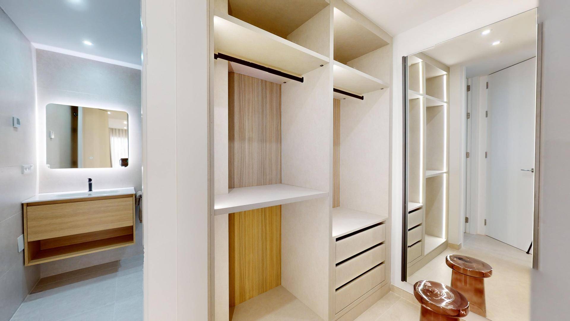 Moderner begehbarer Kleiderschrank mit integrierten Regalen und Schubladen, angrenzend an ein Badezimmer.