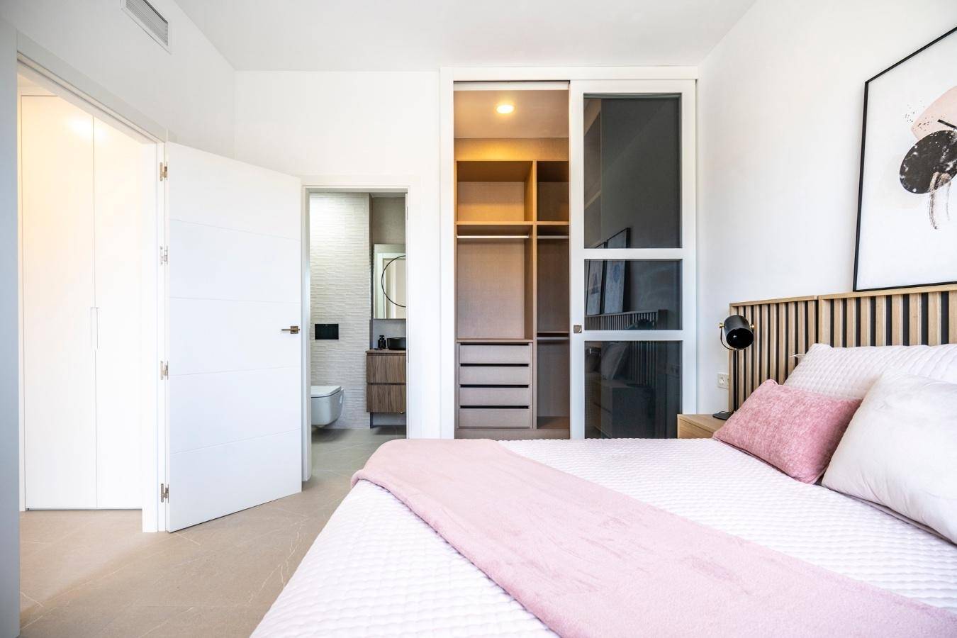 Schlafzimmer mit Zugang zu einem begehbaren Kleiderschrank und einem modernen Ensuite-Badezimmer.