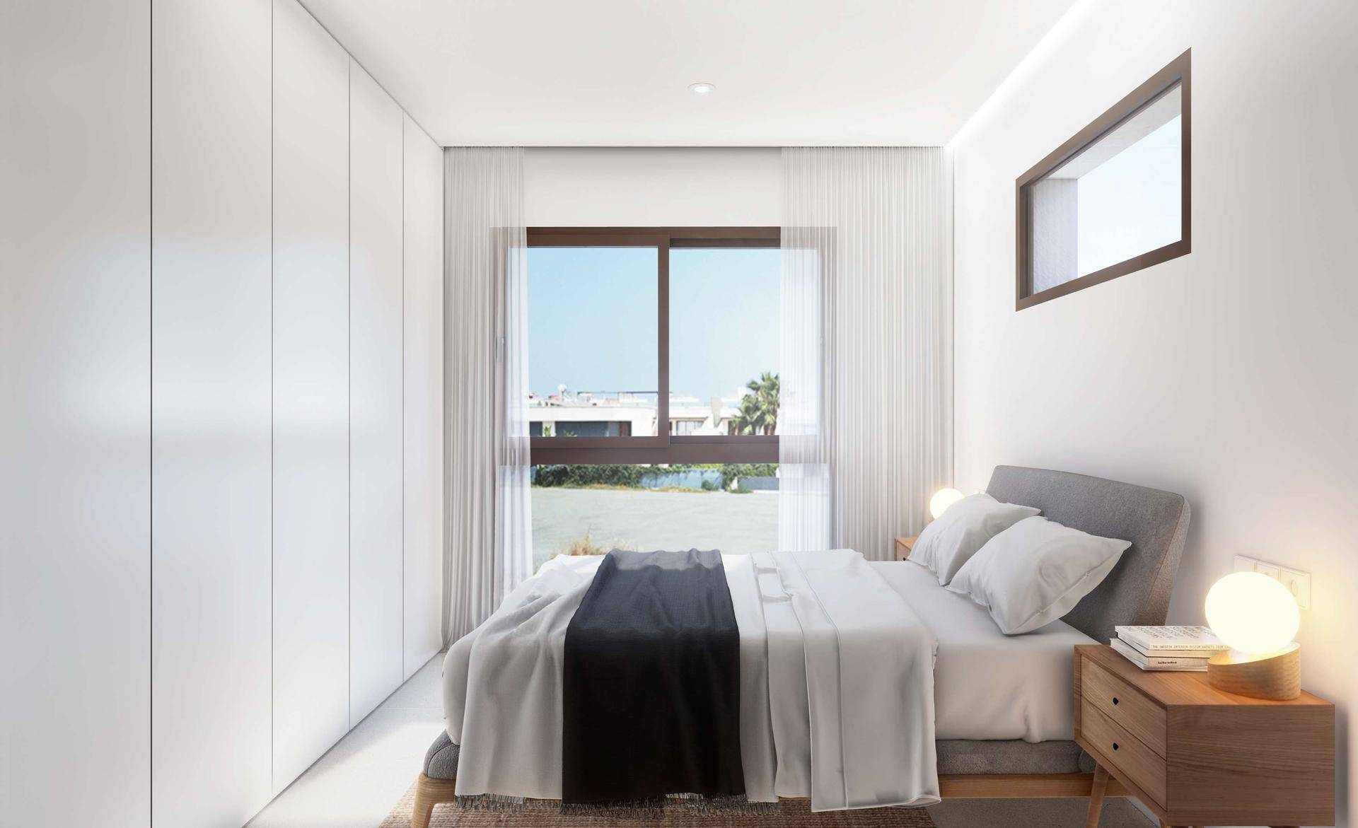 Helles Schlafzimmer mit Einbauschränken und großem Fenster.