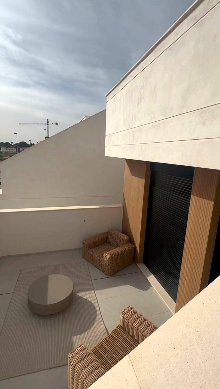 Gemütliche Terrasse mit Rattanmöbeln und modernem Design unter hellem Himmel.