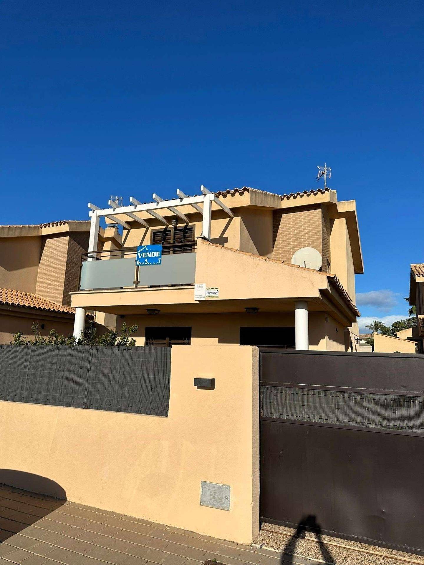 Nahaufnahme der Hausfassade mit Balkon, Pergola und einem Satellitenempfänger an der Wand.