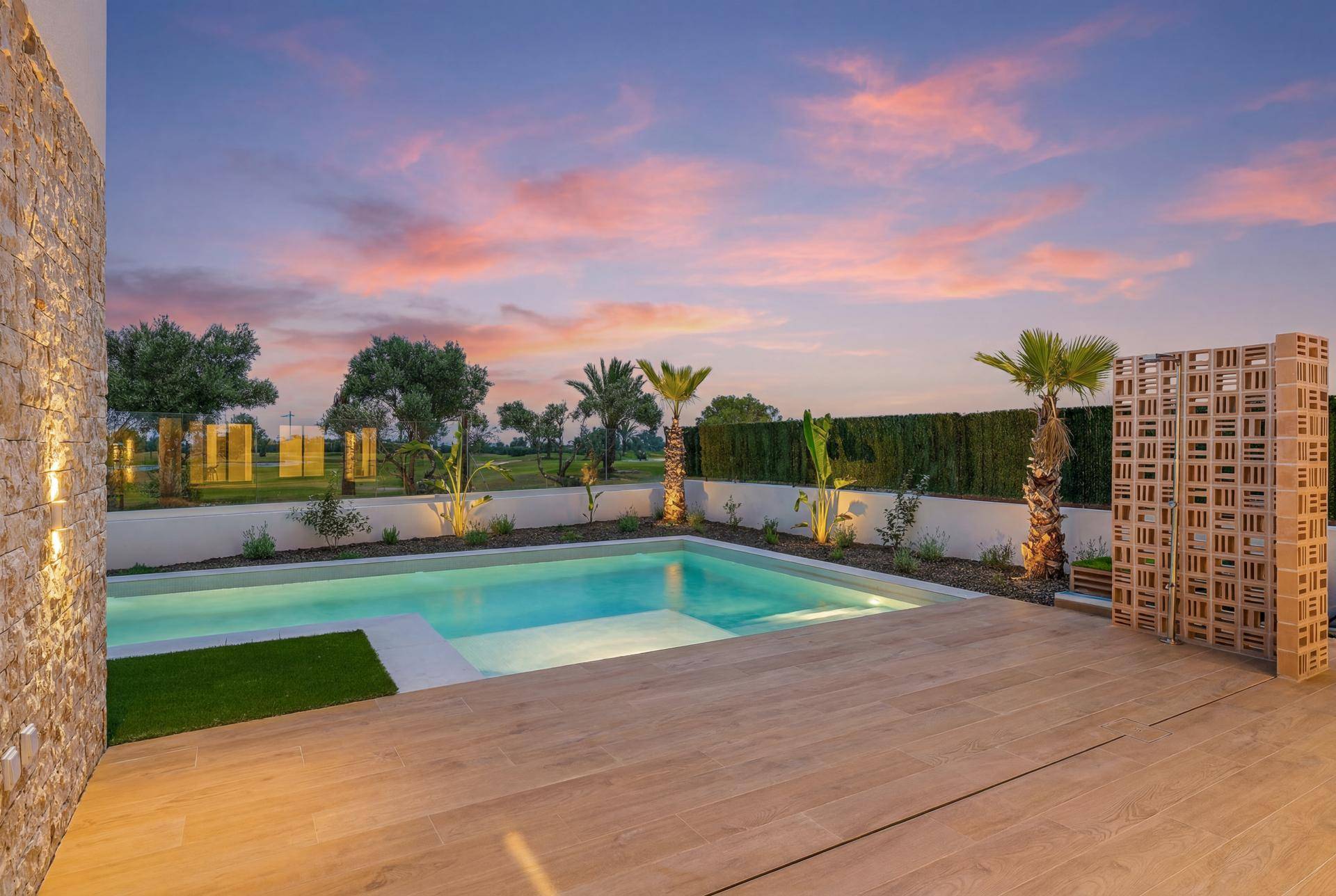 Malerischer Außenbereich mit Pool und Holzterrasse bei Sonnenuntergang, mit Blick auf den Golfplatz.