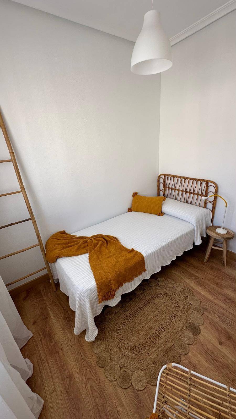 Schlafzimmer mit Einzelbett, Holzboden und einem dekorativen Leiterregal.