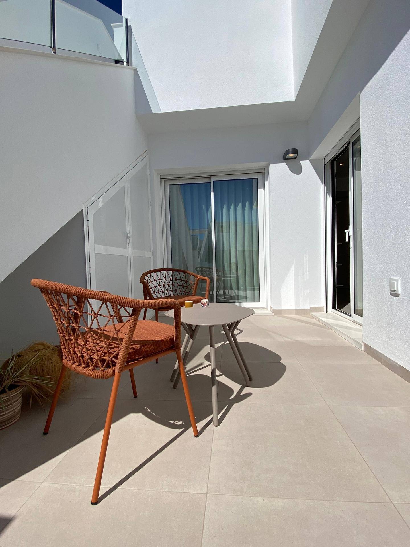 Sonniger Balkon mit Fliesenboden und zwei Stühlen, ideal für eine Kaffeepause.