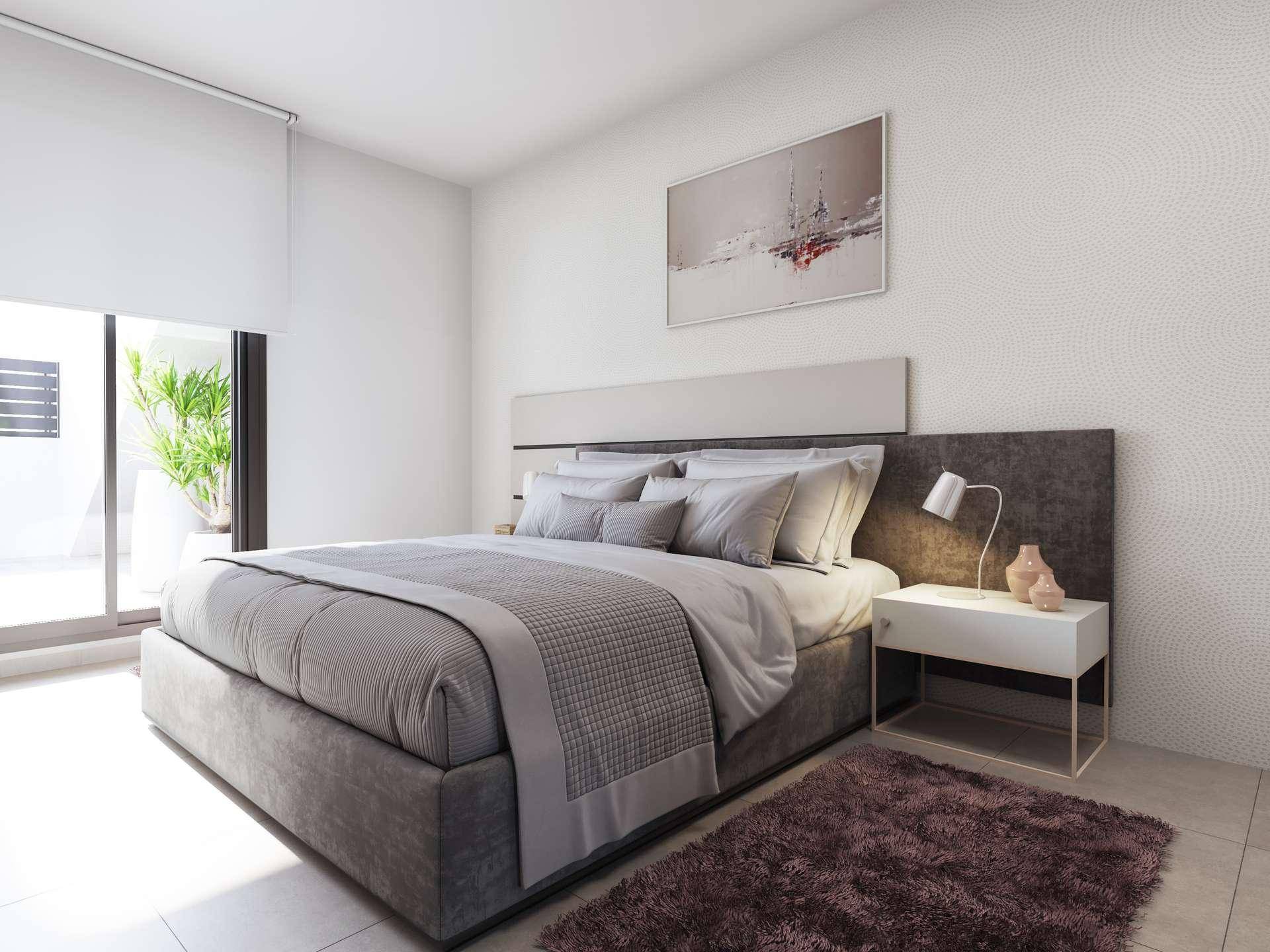 Schlafzimmer mit großem Doppelbett, moderner Einrichtung und Zugang zu einem sonnigen Balkon.