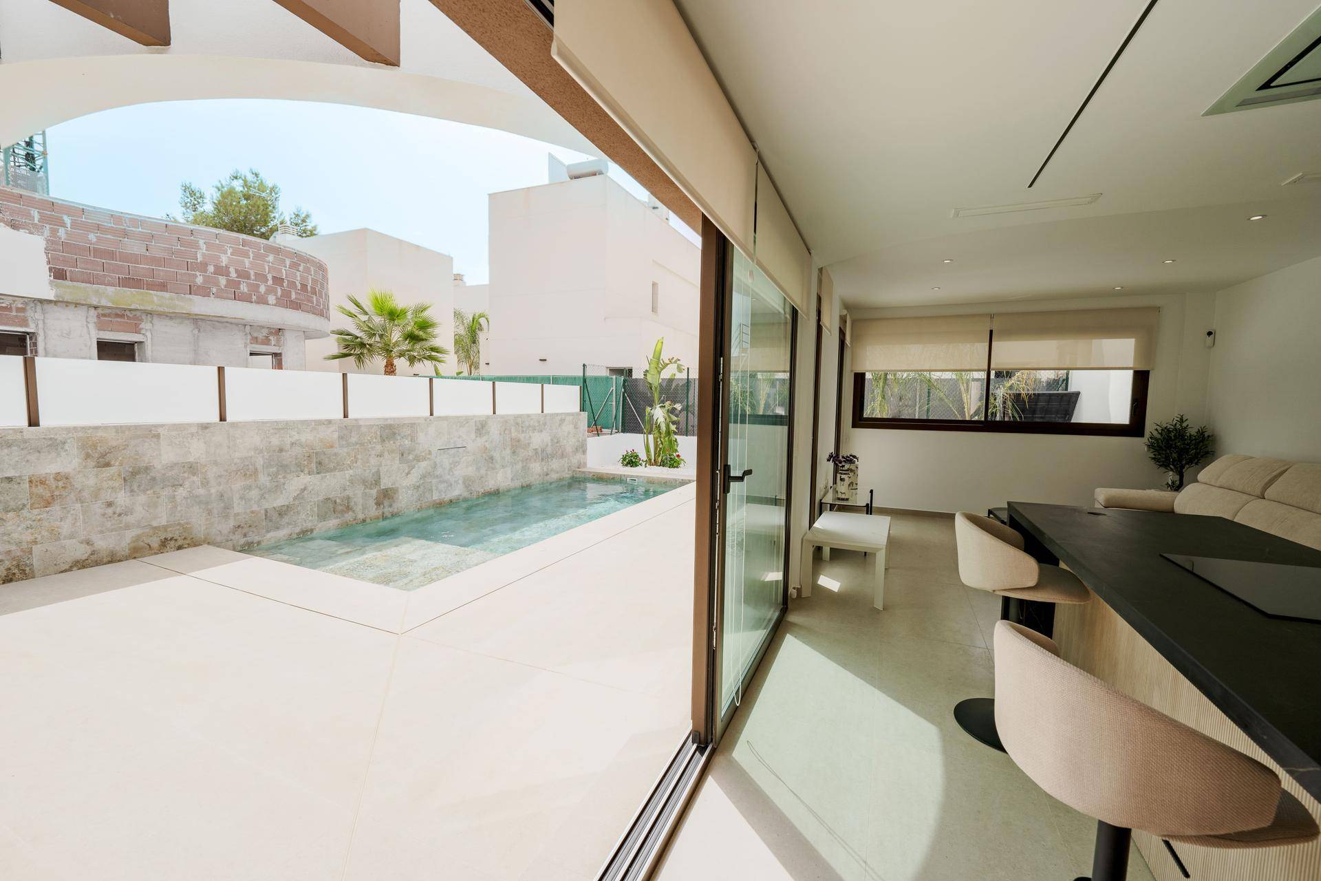 Heller Wohnbereich mit Blick auf den privaten Pool durch große Glasschiebetüren, schafft eine offene Atmosphäre.