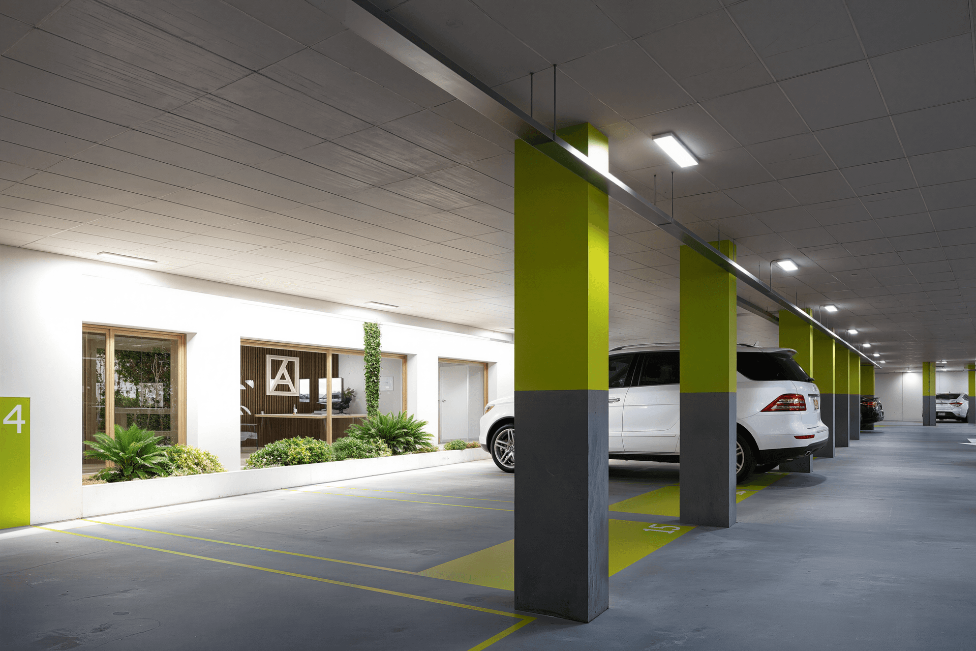 Moderne Tiefgarage mit hellen Säulen und Pflanzen, die eine angenehme Atmosphäre schaffen.