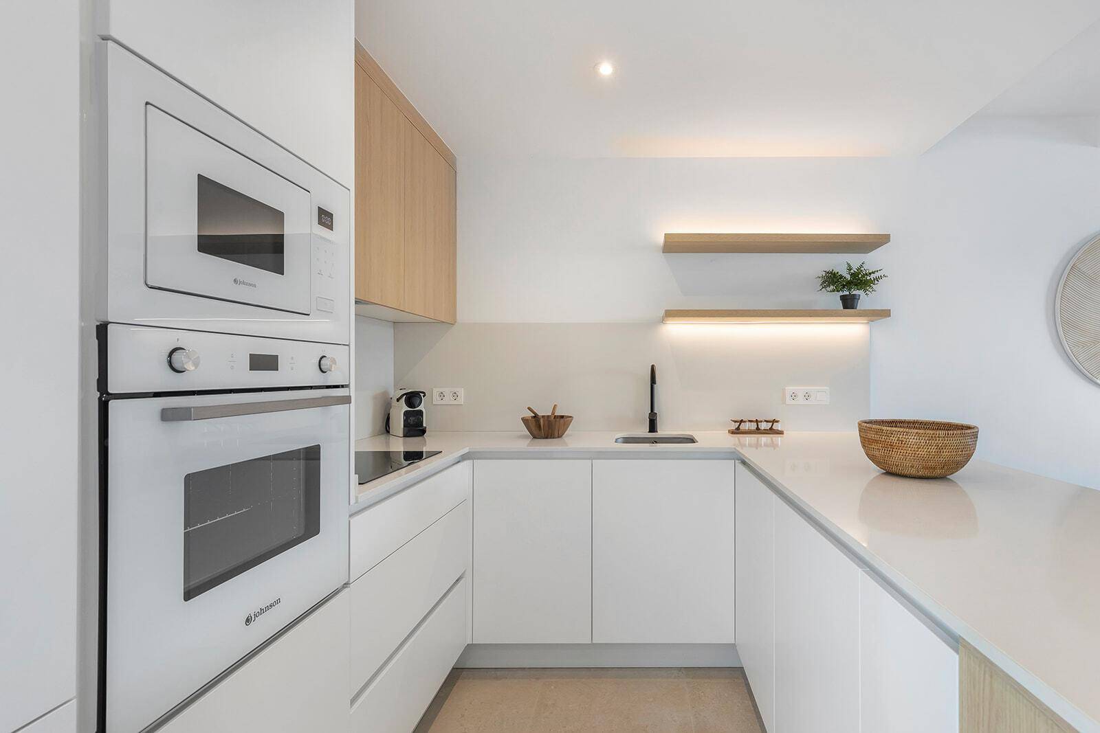 Detailansicht der modernen Küche mit weißen Schränken, integrierten Geräten und minimalistischem Design.