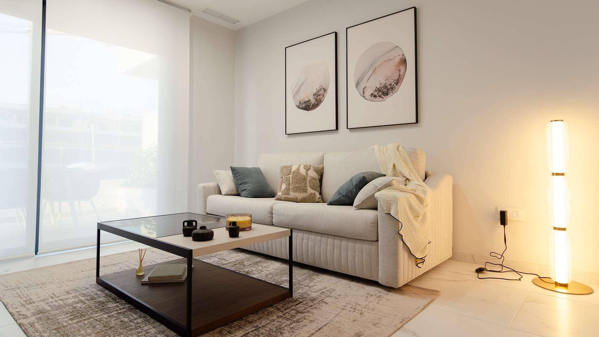 Helles Wohnzimmer mit modernem Sofa, Couchtisch und stilvollen Bildern an der Wand.