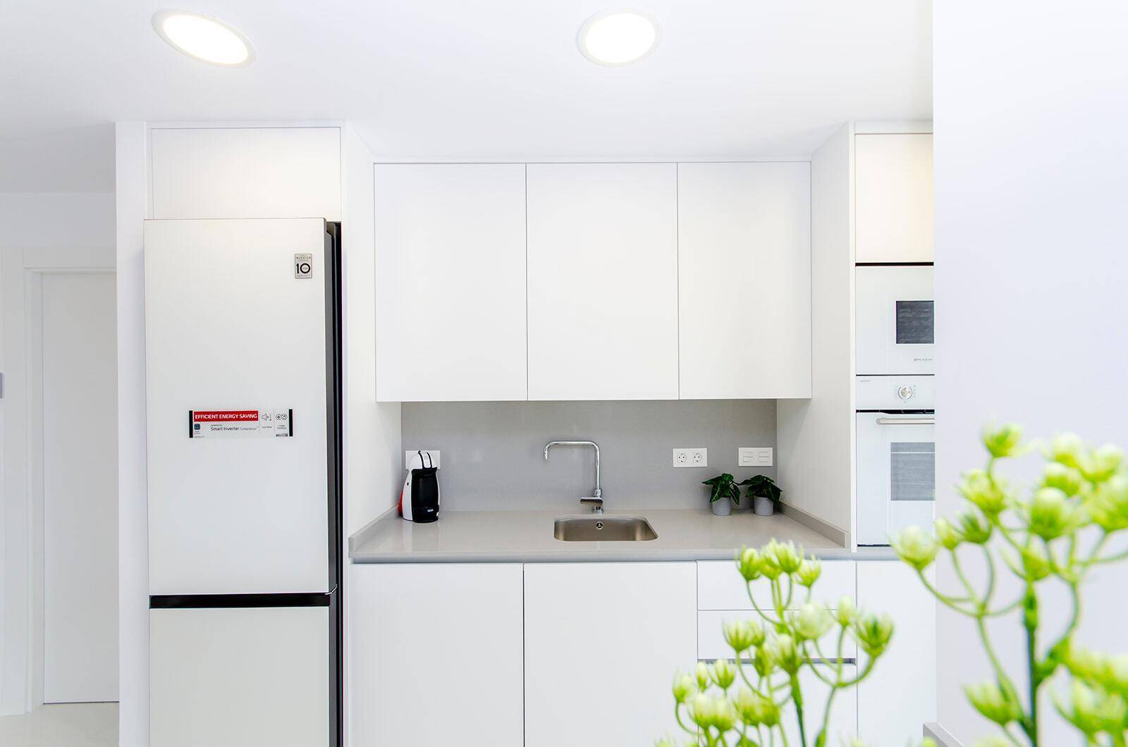 Moderne weiße Küche mit integrierten Geräten und minimalistischem Design.