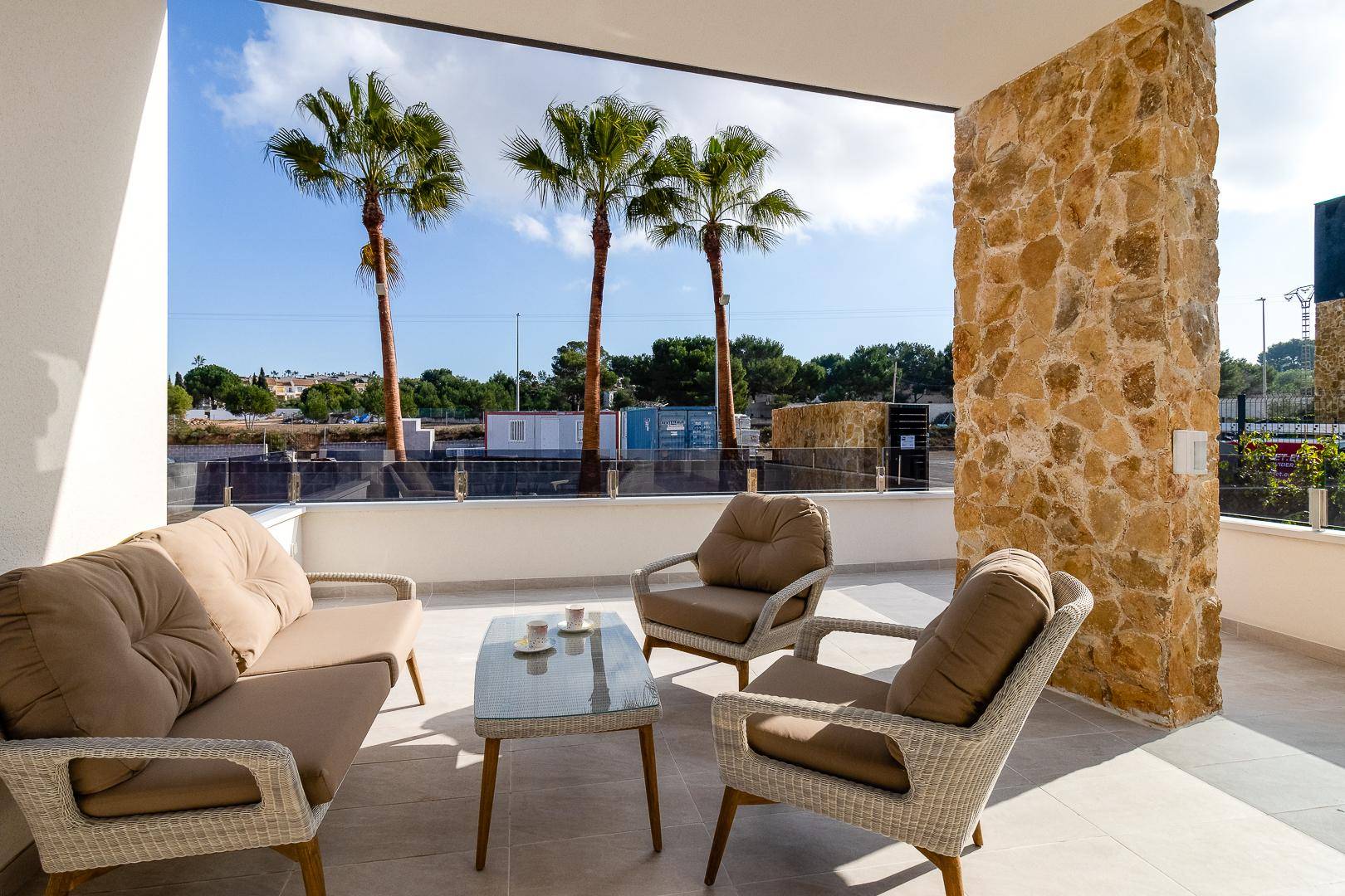 Geräumige Terrasse mit bequemen Sitzmöbeln, Palmen und weitem Blick in die Landschaft.