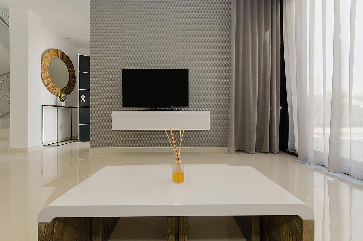 Moderner Wohnbereich mit Wandfernseher, stilvoller Tapete und großem Couchtisch.