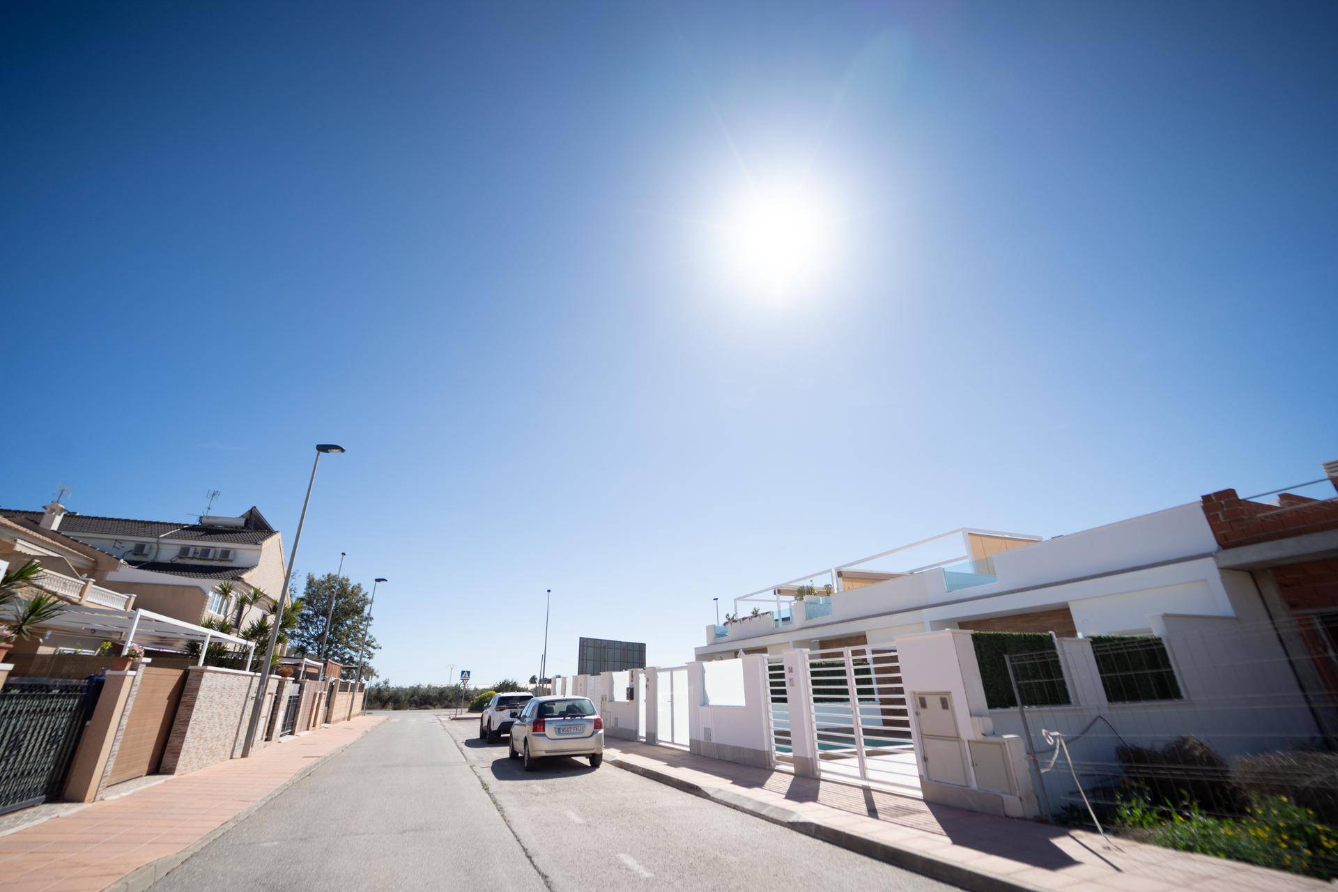 Sonniger Straßenblick mit modernen Häusern und klarem blauem Himmel in einer Wohngegend.