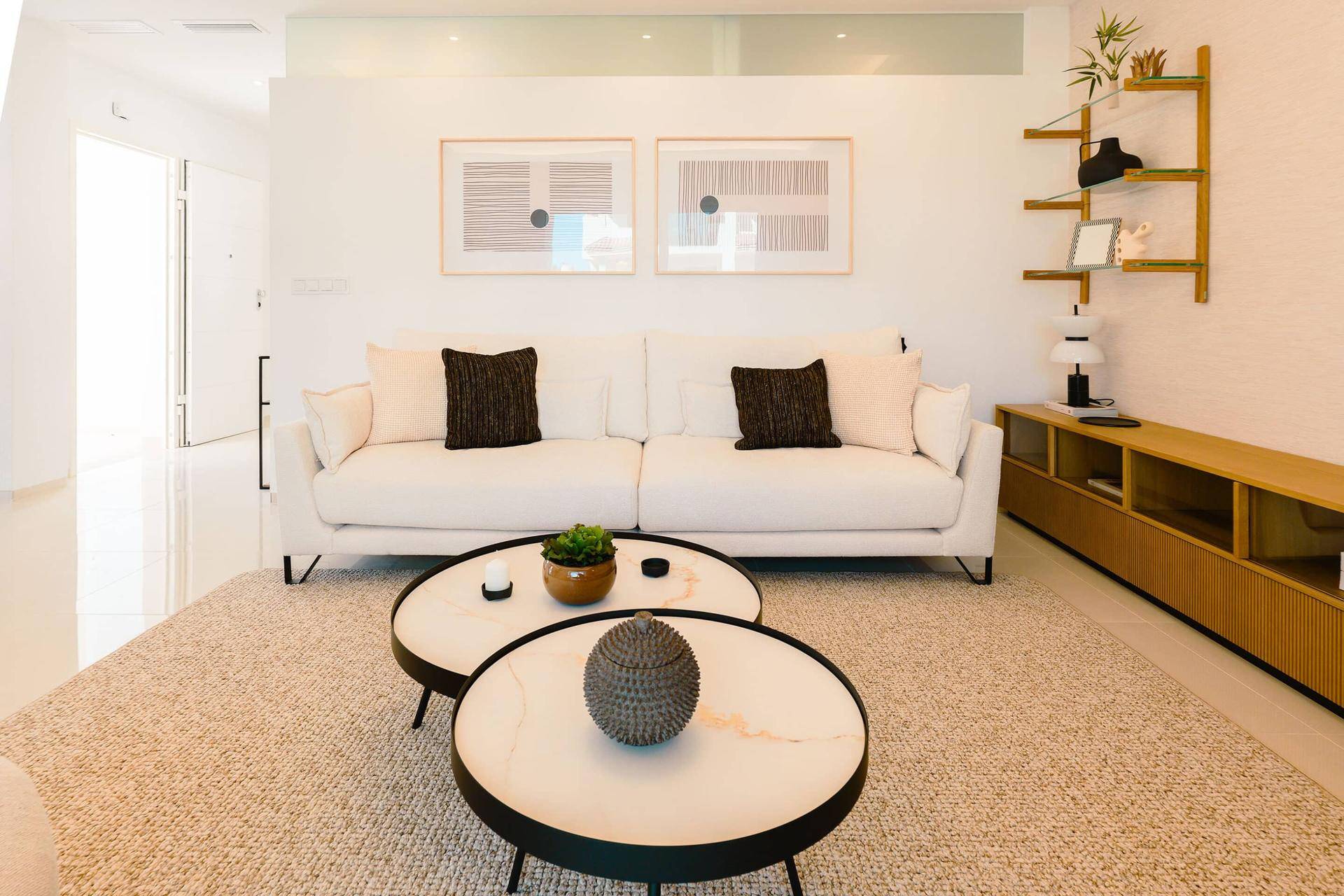 Stilvolles Wohnzimmer mit hellem Sofa, Couchtischen und moderner Wanddekoration.