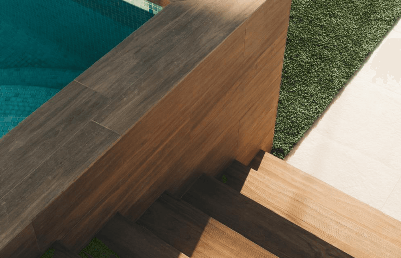 Detailansicht von Holzstufen und Poolbereich mit Kunstrasen.