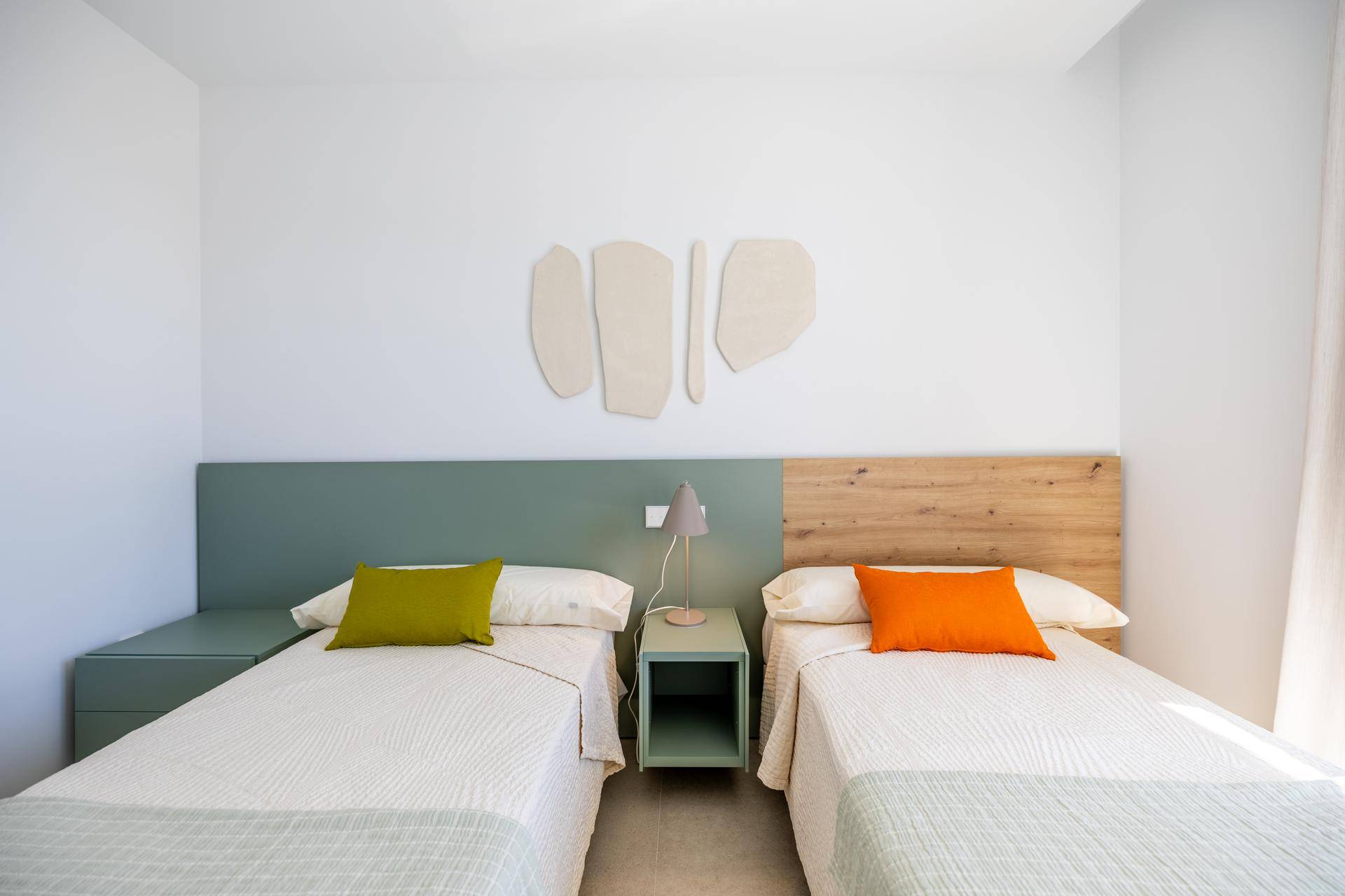Freundliches Schlafzimmer mit zwei Einzelbetten, farbigen Akzenten und moderner Dekoration.