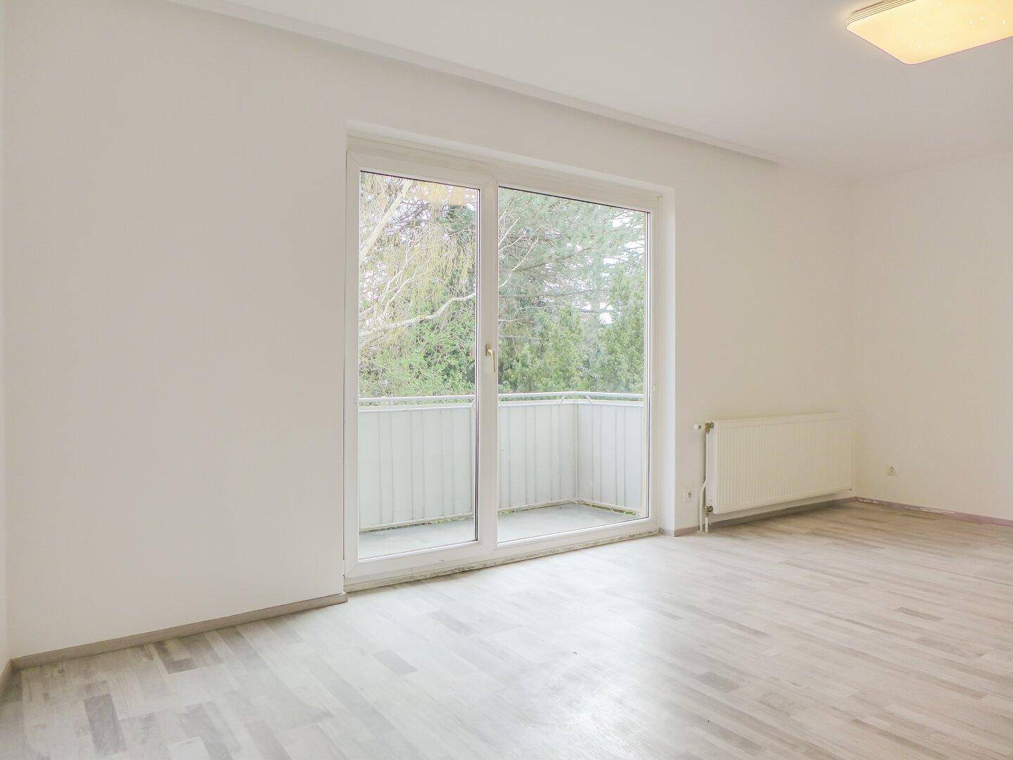 Geräumiges, helles Zimmer mit Balkonzugang und Heizkörper, bereit zur individuellen Gestaltung.