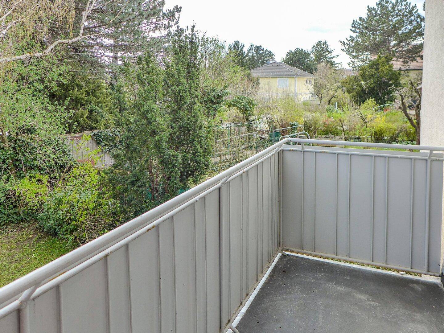 Leerer Balkon mit Metallgeländer und weitem Blick auf die umliegende grüne Landschaft.
