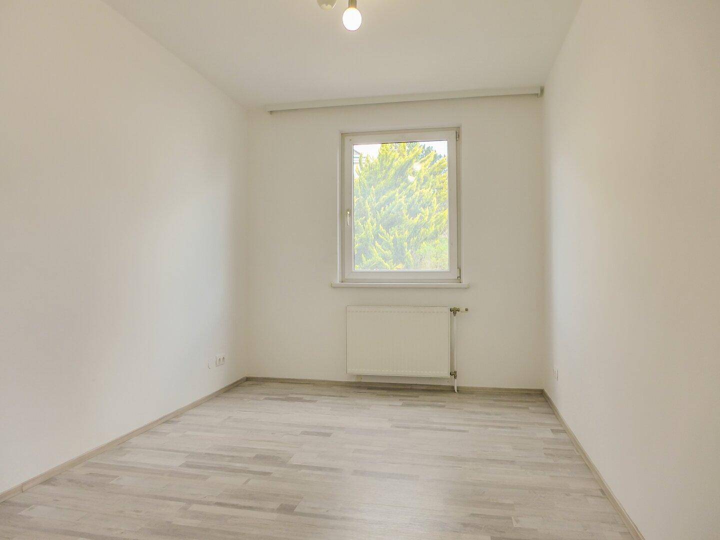 Leeres Zimmer mit Fenster und Blick ins Grüne, perfekt als Schlaf- oder Arbeitszimmer.